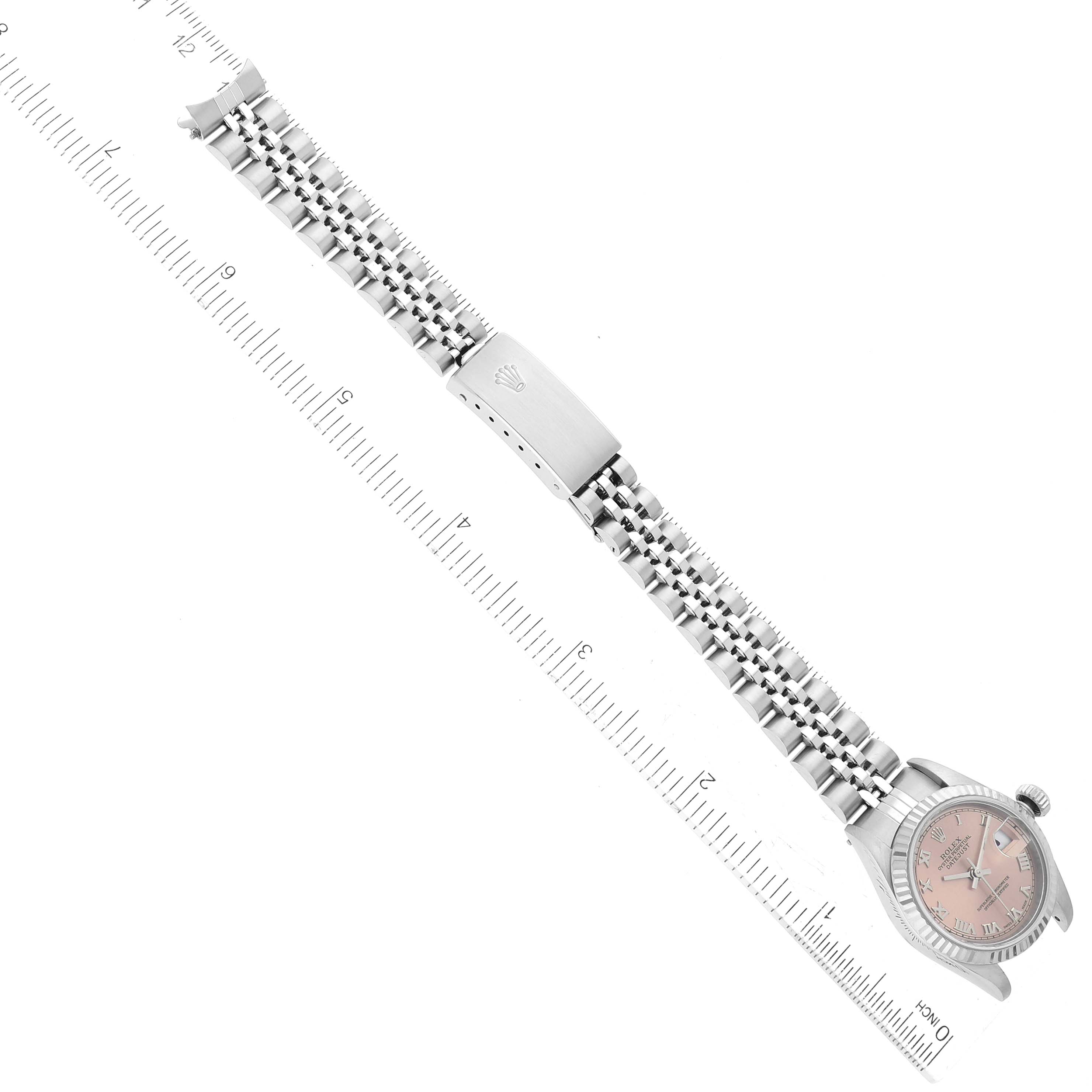 The image shows a top-down view of a Rolex Datejust 79174 Women's Stainless Steel Pink Dial 79174 Women's Stainless Steel Pink Dial watch, displaying the face, bezel, and bracelet laid next to a ruler for scale.