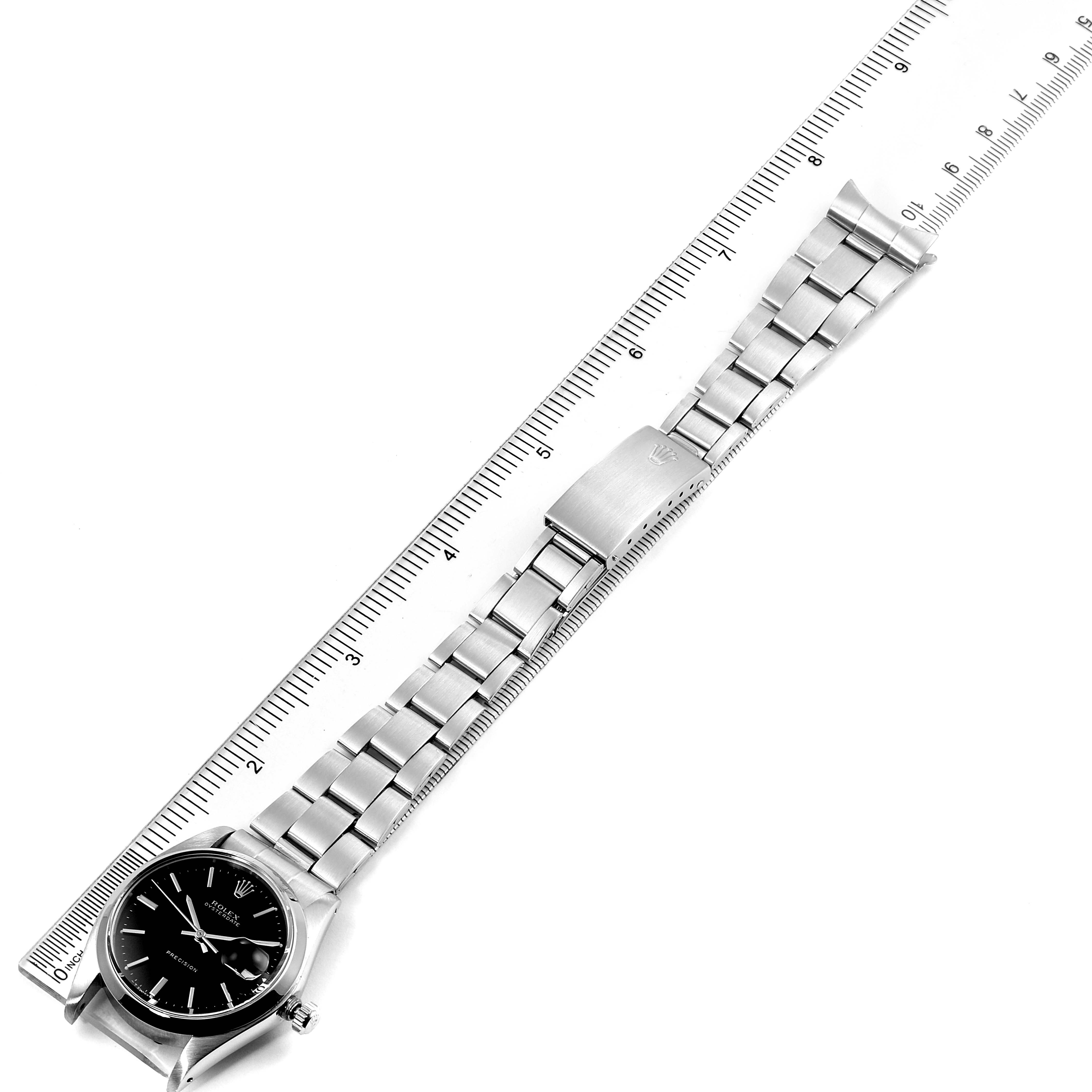 The image shows a Rolex Vintage Collection 6694 Men
s Stainless Steel Black Dial 6694 Men
s Stainless Steel Black Dial watch from an overhead angle, displaying the face, bracelet, and clasp, along with a ruler for scale.