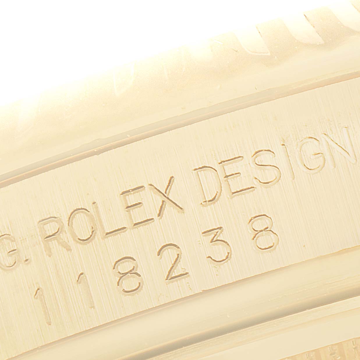 This image shows a close-up of the case engraving on a Rolex President 118238 Men
s Yellow Gold White Dial 118238 Men
s Yellow Gold White Dial model watch, displaying "ROLEX DESIGN" and its serial number.