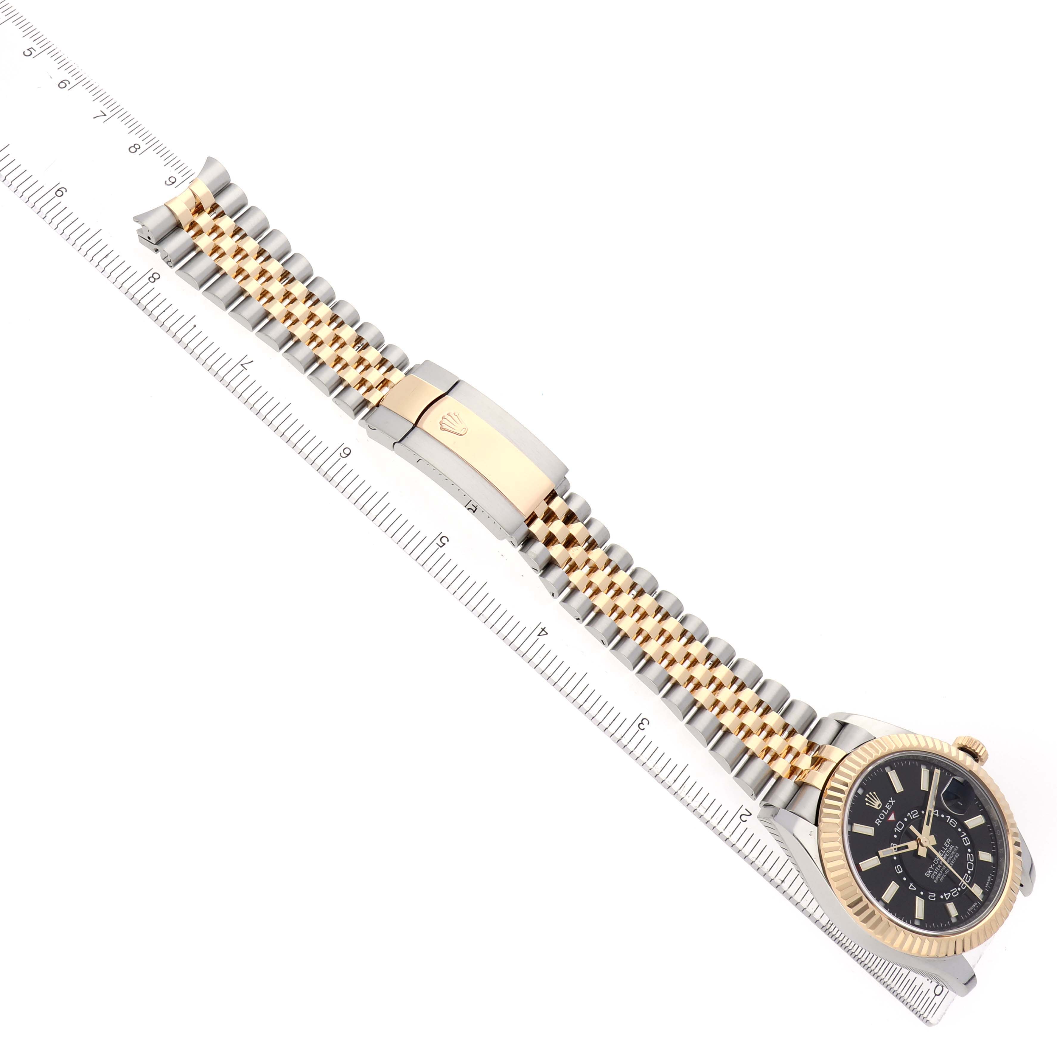 The image shows the Rolex Sky-Dweller 326933 Men's Steel and Gold (two tone) Black Dial watch laid flat with the bracelet, case, and bezel visible, aligned with a ruler.
