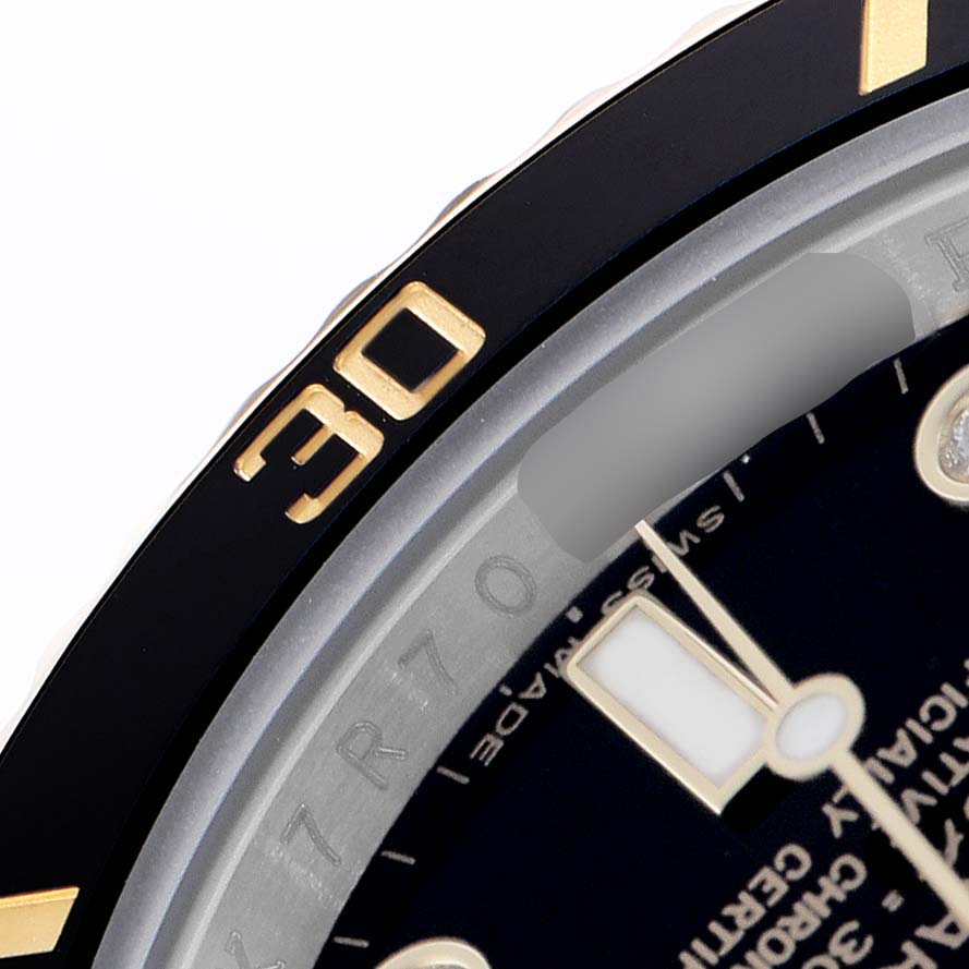 The image shows a close-up of the Rolex Submariner 116613 Men's Steel and Gold (two tone) Black Dial's bezel, dial, and part of the watch face, focusing on the minute hand and details.