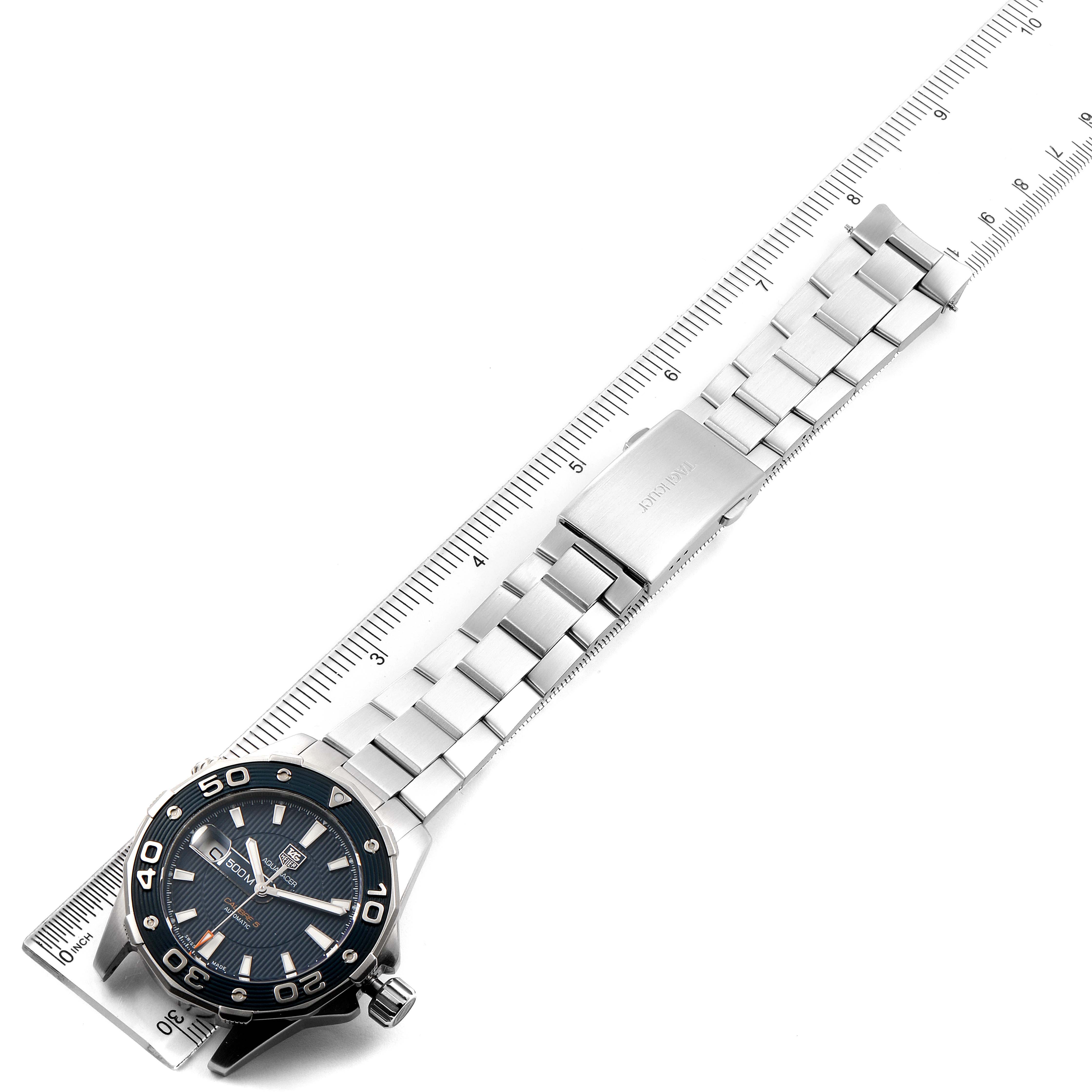 The image shows an overhead view of a Tag Heuer Aquaracer WAJ2112  Men
s Stainless Steel Blue Dial WAJ2112  Men
s Stainless Steel Blue Dial watch, including its face, bezel, and metal bracelet, placed alongside a ruler.