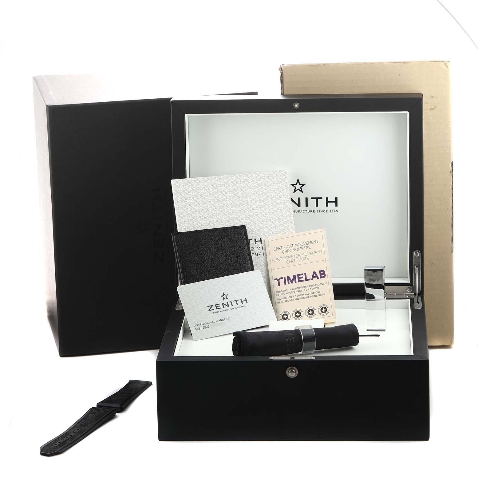 The image shows a Zenith Defy 10.9000.9004 Men's Titanium Blue Dial watch box with accessories, a strap, and documentation from a slightly elevated angle.