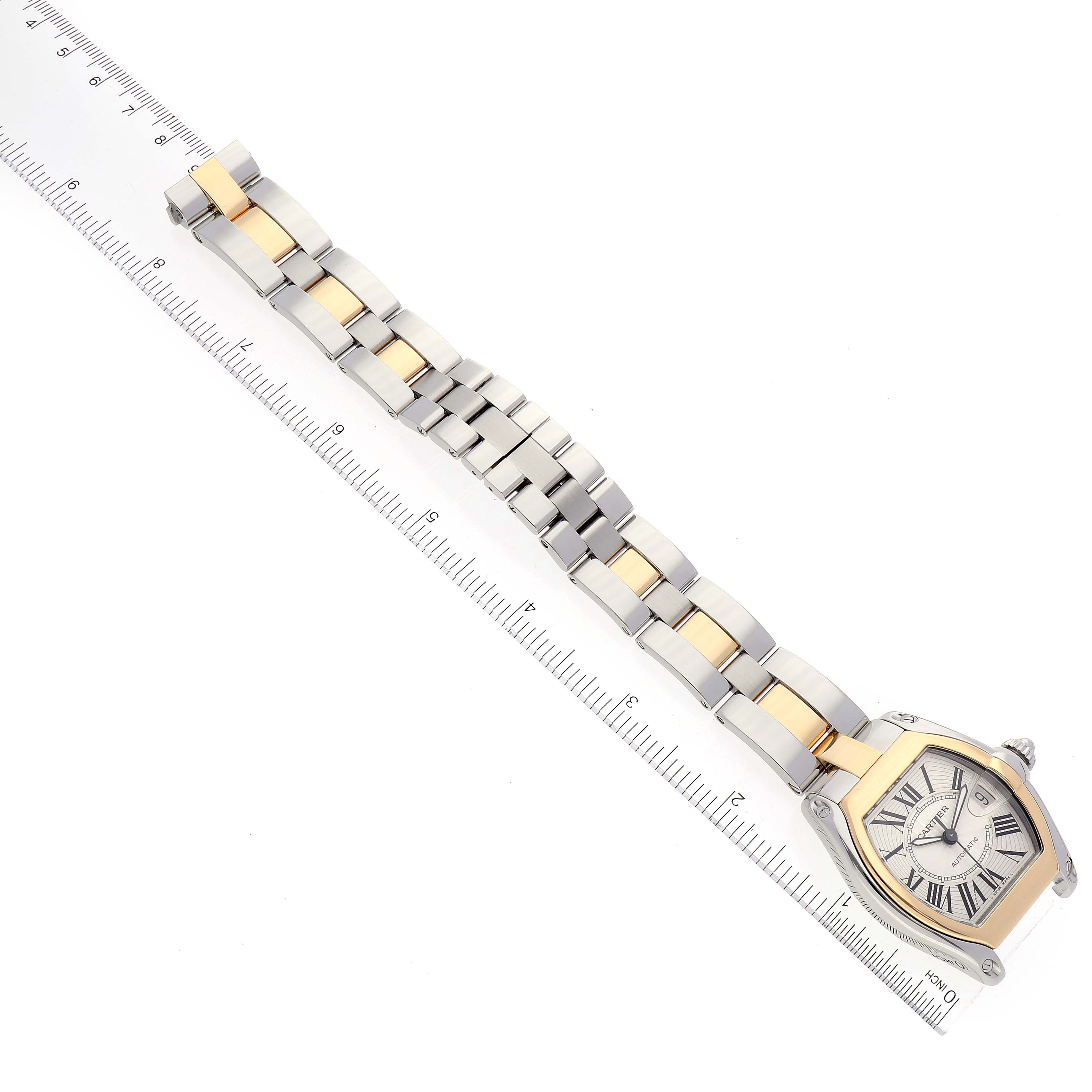 This image shows a Cartier Roadster W62031Y4 Men's Steel and Gold (two tone) Silver Dial W62031Y4 Men's Steel and Gold (two tone) Silver Dial watch viewed from above, displaying its face and dual-tone metal bracelet, placed beside a ruler.