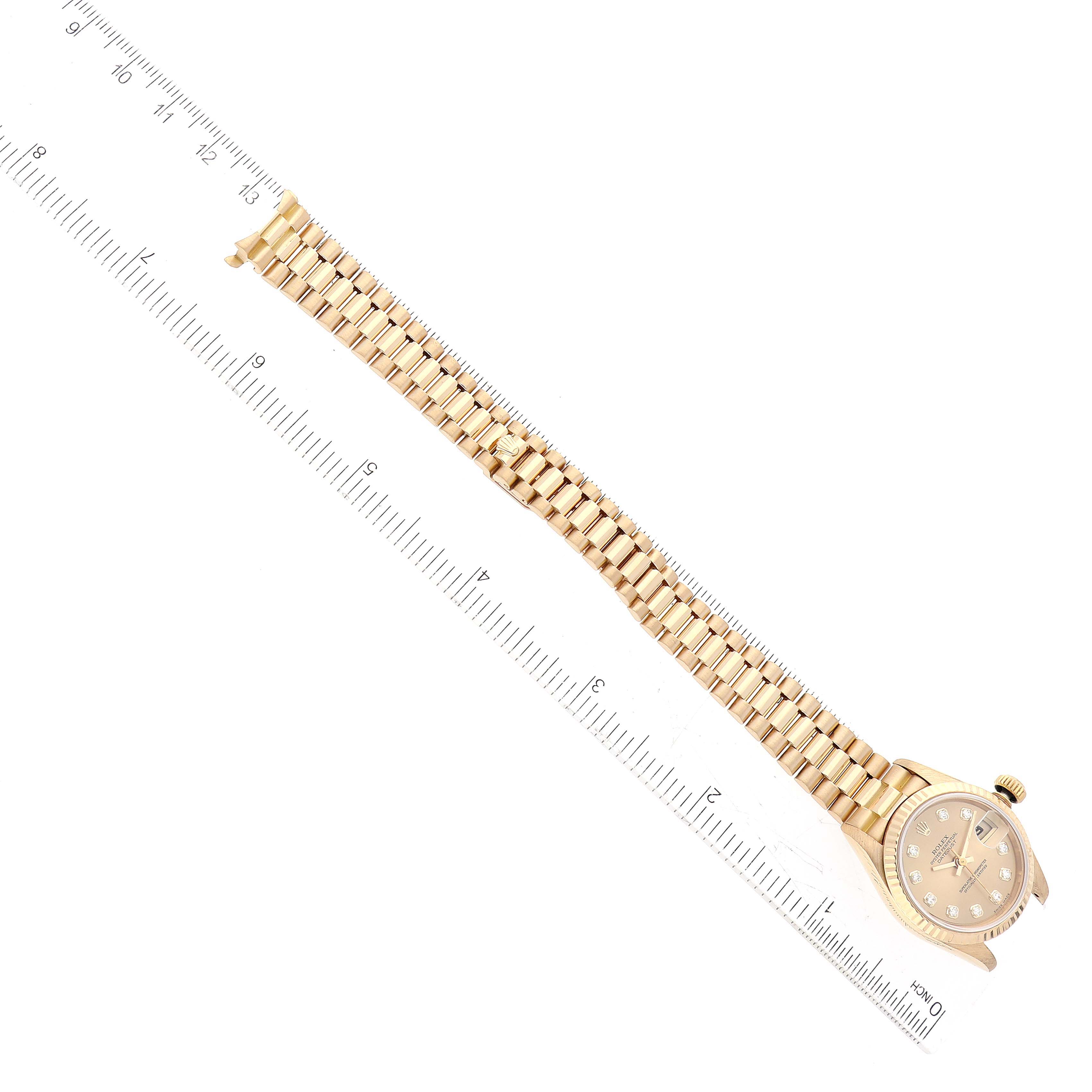 The image shows a top view of a Rolex President 69178 Women's Yellow Gold Champagne Dial 69178 Women's Yellow Gold Champagne Dial model watch with its face, case, and linked bracelet band next to a ruler.