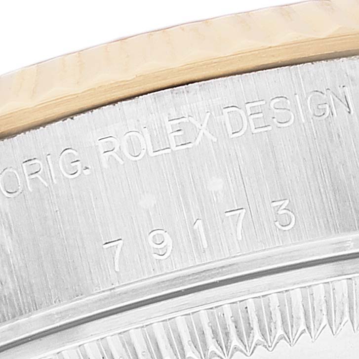 This is a close-up shot of the side of a Rolex Datejust 79173 Women's Steel and Gold (two tone) Champagne Dial 79173 Women's Steel and Gold (two tone) Champagne Dial watch, showing the engraving and part of the bezel.