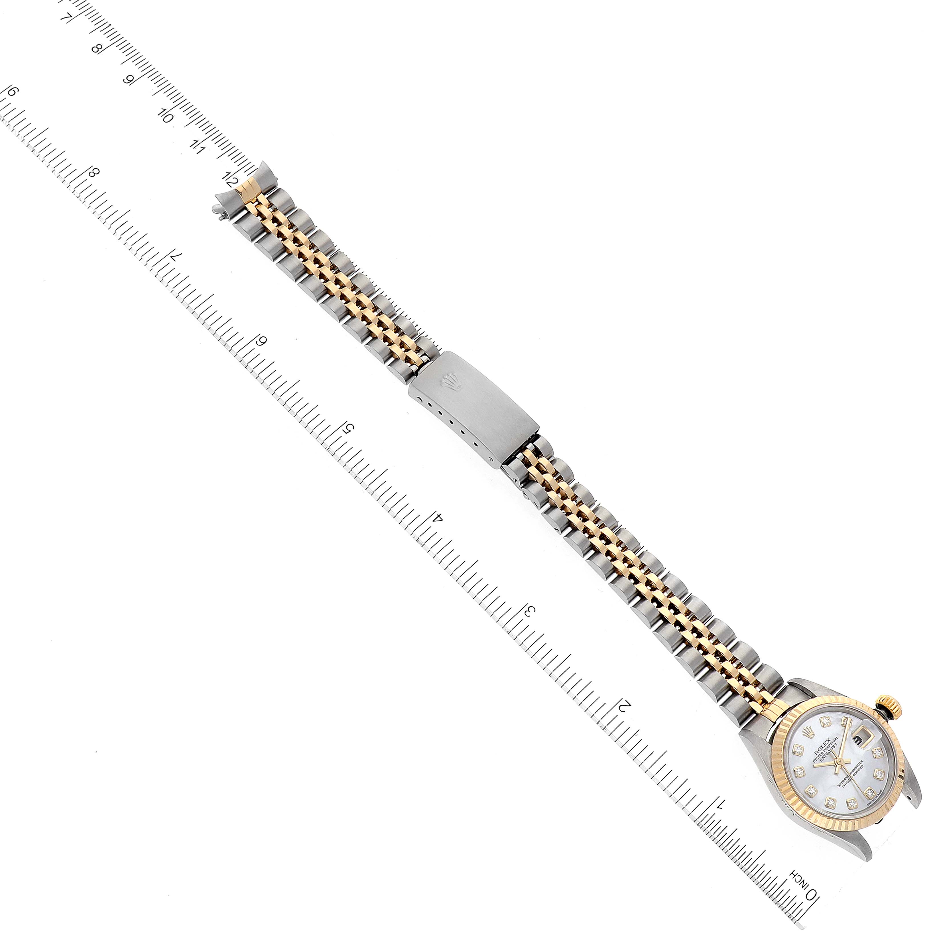 This image shows a Rolex Datejust 79173 Women's Steel and Gold (two tone) Mother of Pearl Dial 79173 Women's Steel and Gold (two tone) Mother of Pearl Dial watch laid flat, displaying the dial, bezel, bracelet, and clasp next to a ruler for scale.