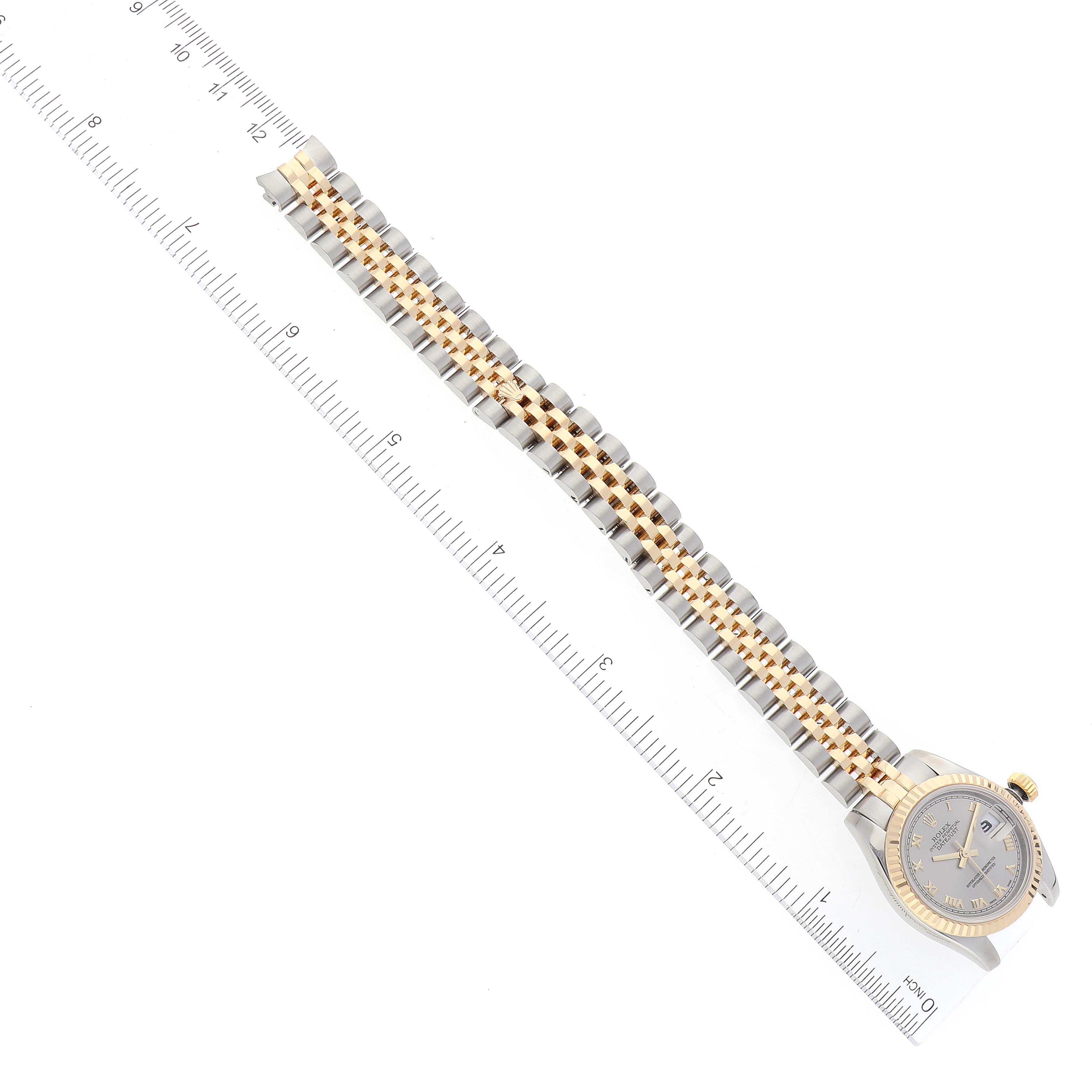 The Rolex Datejust 179173 Women's Steel and Gold (two tone) Grey Dial 179173 Women's Steel and Gold (two tone) Grey Dial watch is shown flat with a full display of its bracelet and face, placed alongside a ruler for measuring length.