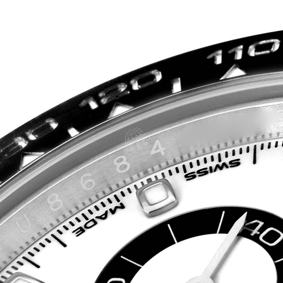 The image shows the bezel and part of the dial of a Rolex Daytona 116500 Men's Stainless Steel White Dial 116500 Men's Stainless Steel White Dial watch, highlighting the tachymeter scale and some numerals.