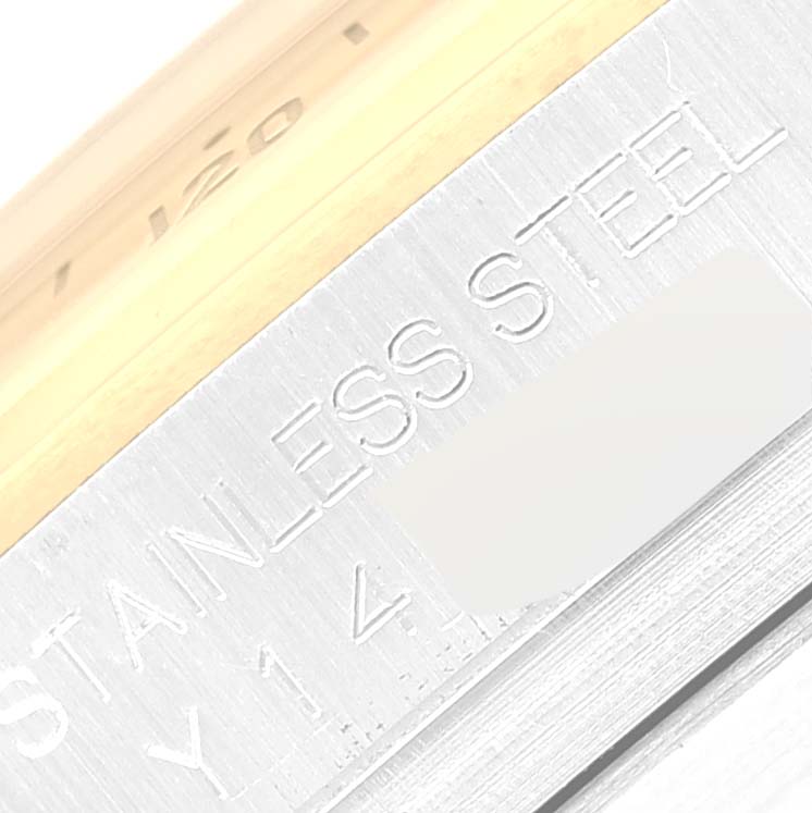 This close-up image shows a portion of the stainless steel case side and engraved text of a Rolex Daytona 116523 Men's Steel and Gold (two tone) White Dial 116523 Men's Steel and Gold (two tone) White Dial watch.