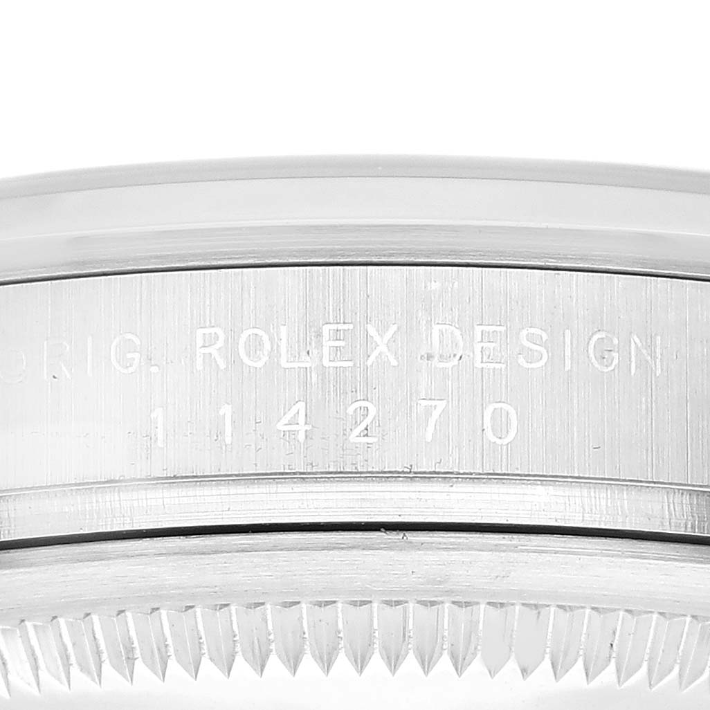 The image shows a close-up of the side of a Rolex Explorer 114270 Men's Stainless Steel Black Dial 114270 Men's Stainless Steel Black Dial model, highlighting the engraved "ROLEX DESIGN" and reference number.