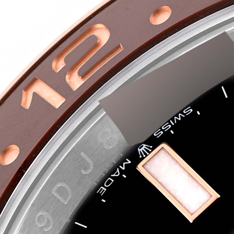 Close-up of the Rolex GMT-Master 126711CHNR Men's Steel and Gold (two tone) Black Dial 126711CHNR Men's Steel and Gold (two tone) Black Dial watch bezel showing the "12" marker and part of the dial reading "SWISS MADE".