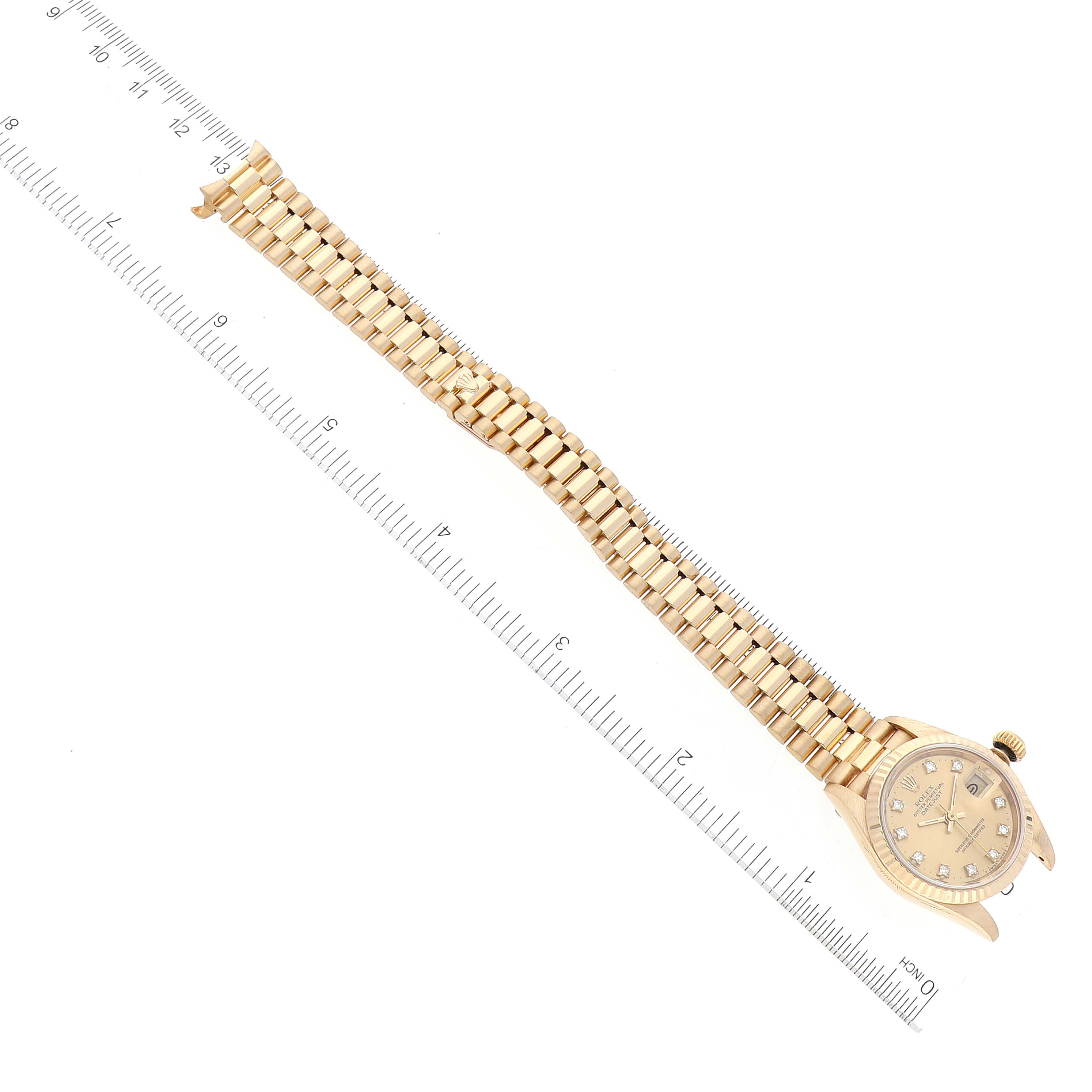 The image shows a Rolex President 69178 Women's Yellow Gold Champagne Dial 69178 Women's Yellow Gold Champagne Dial model watch from a top-down angle,  emphasizing the watch band and partially the face, with rulers for scale.