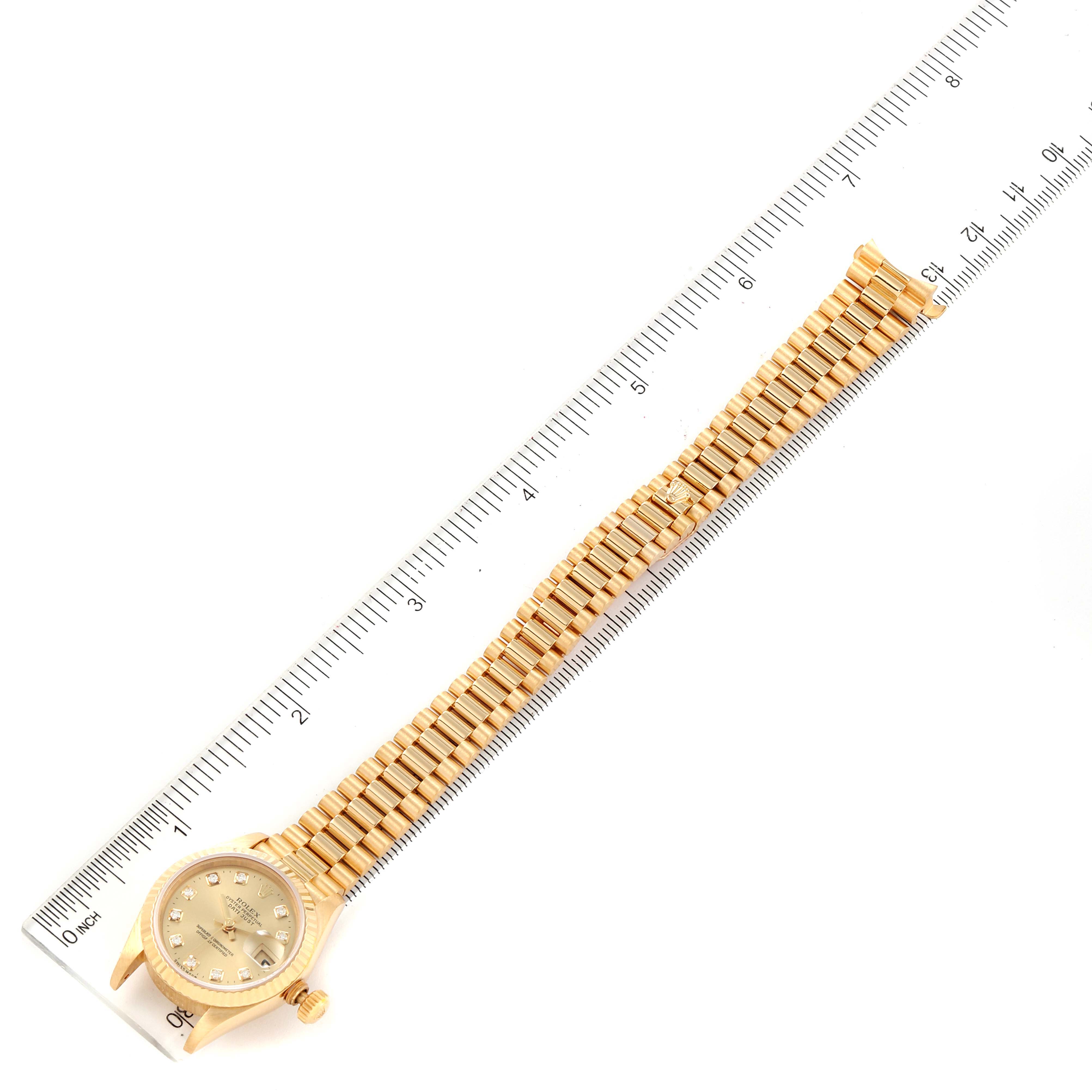 The Rolex President 69178 Women's Yellow Gold Champagne Dial 69178 Women's Yellow Gold Champagne Dial watch is shown laid flat next to a ruler, displaying its entire bracelet and face.