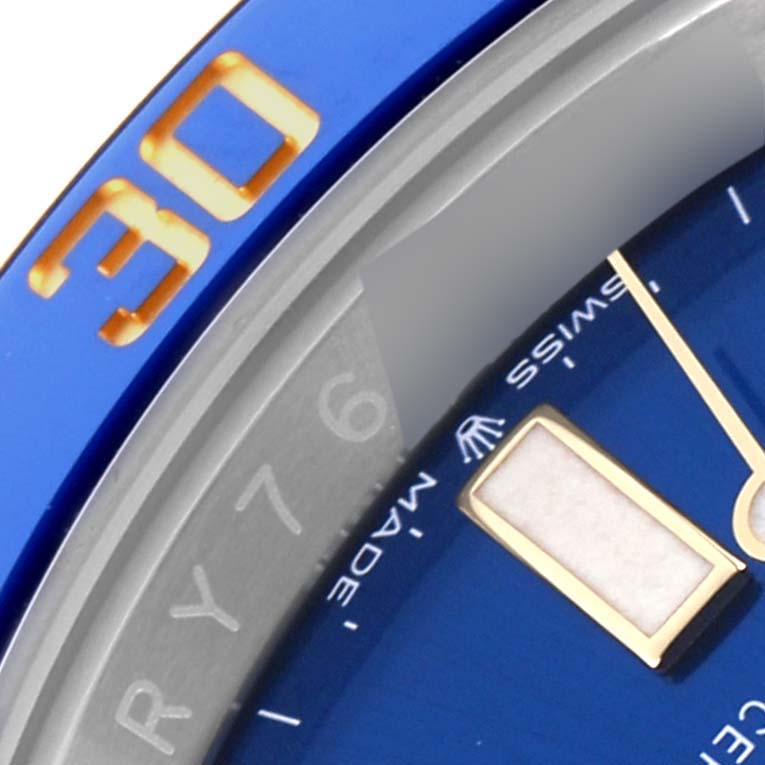 The image shows a close-up of a Rolex Submariner 126613 Men's Steel and Gold (two tone) Blue Dial 126613 Men's Steel and Gold (two tone) Blue Dial's blue bezel and a portion of its dial, including an hour marker.