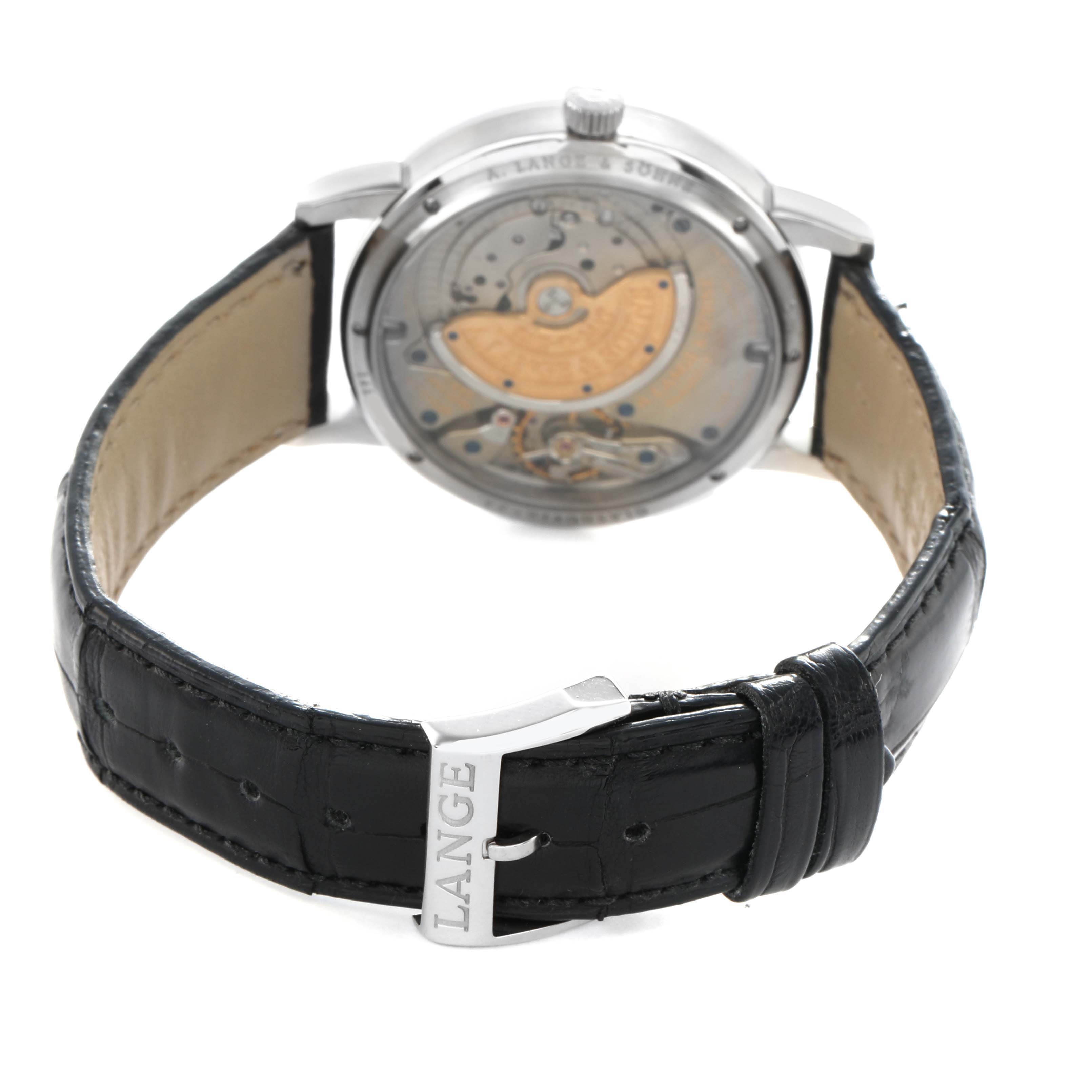 The image shows the back of an A. Lange & Söhne watch with its mechanism visible, and a black leather strap and buckle.