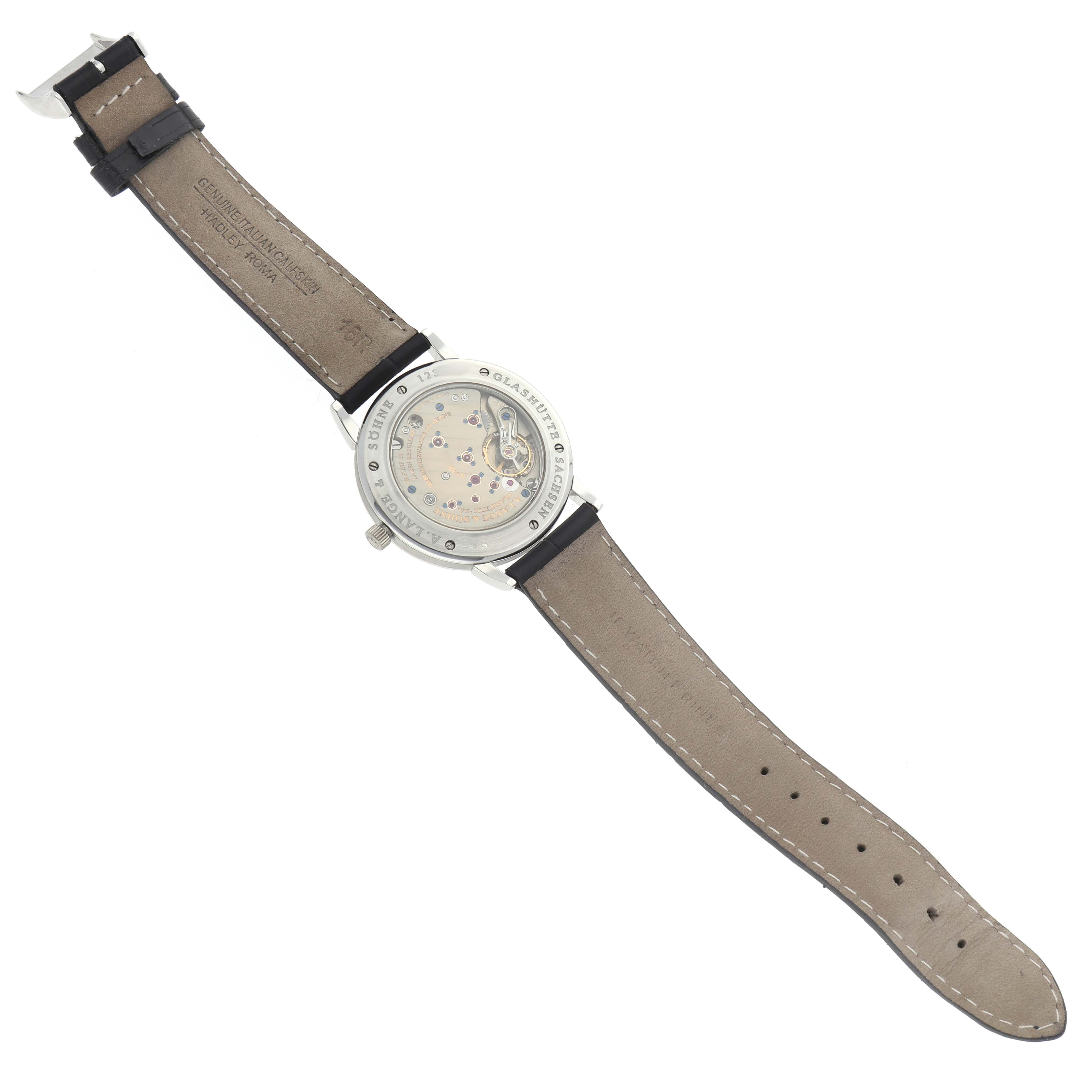 The image shows the back of the A. Lange & Sohne 1815 221.025 Men's Platinum Silver Dial watch, highlighting its movement and leather strap.