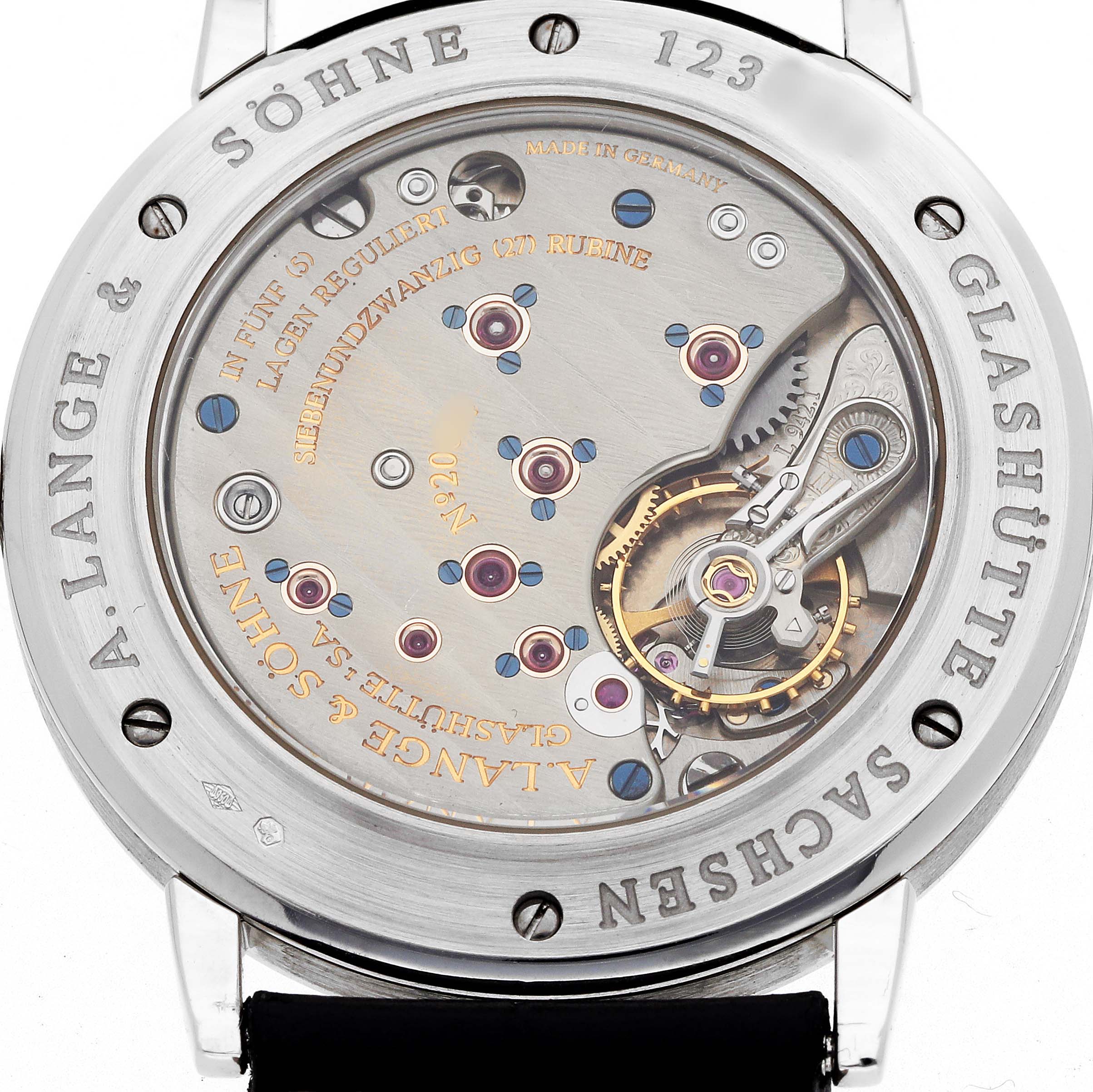 The image shows the case back of the A. Lange & Sohne 1815 221.025 Men's Platinum Silver Dial model, highlighting its intricate mechanical movement and engravings.