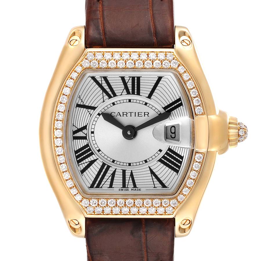 The Cartier Roadster watch is shown from a front angle, featuring a diamond bezel, brown leather strap, and a date window at 3 o'clock.