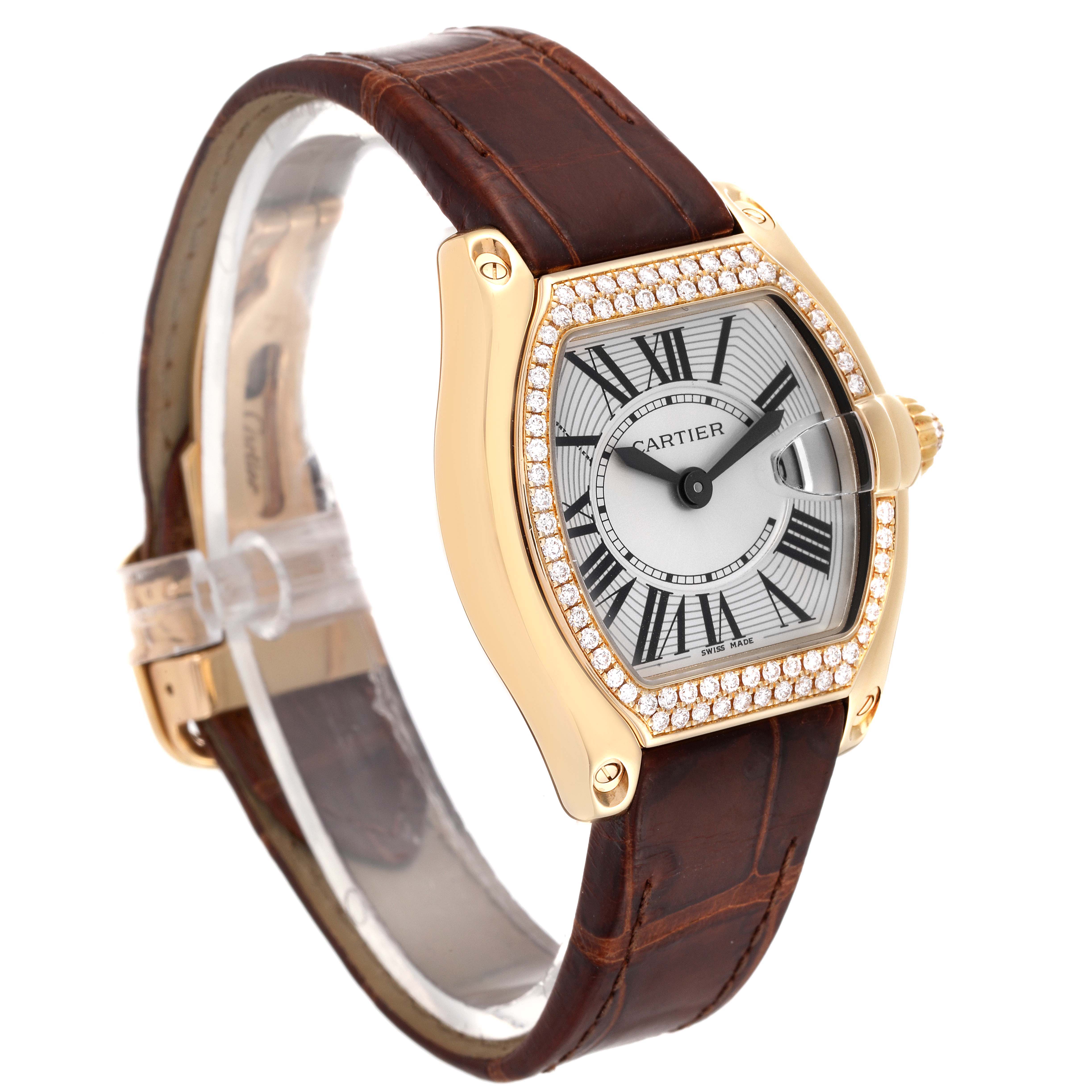 The Cartier Roadster WE500160 Women's Yellow Gold Silver Dial WE500160 Women's Yellow Gold Silver Dial watch is shown at a three-quarter angle, highlighting its gold case, diamond bezel, Roman numeral dial, and brown leather strap.