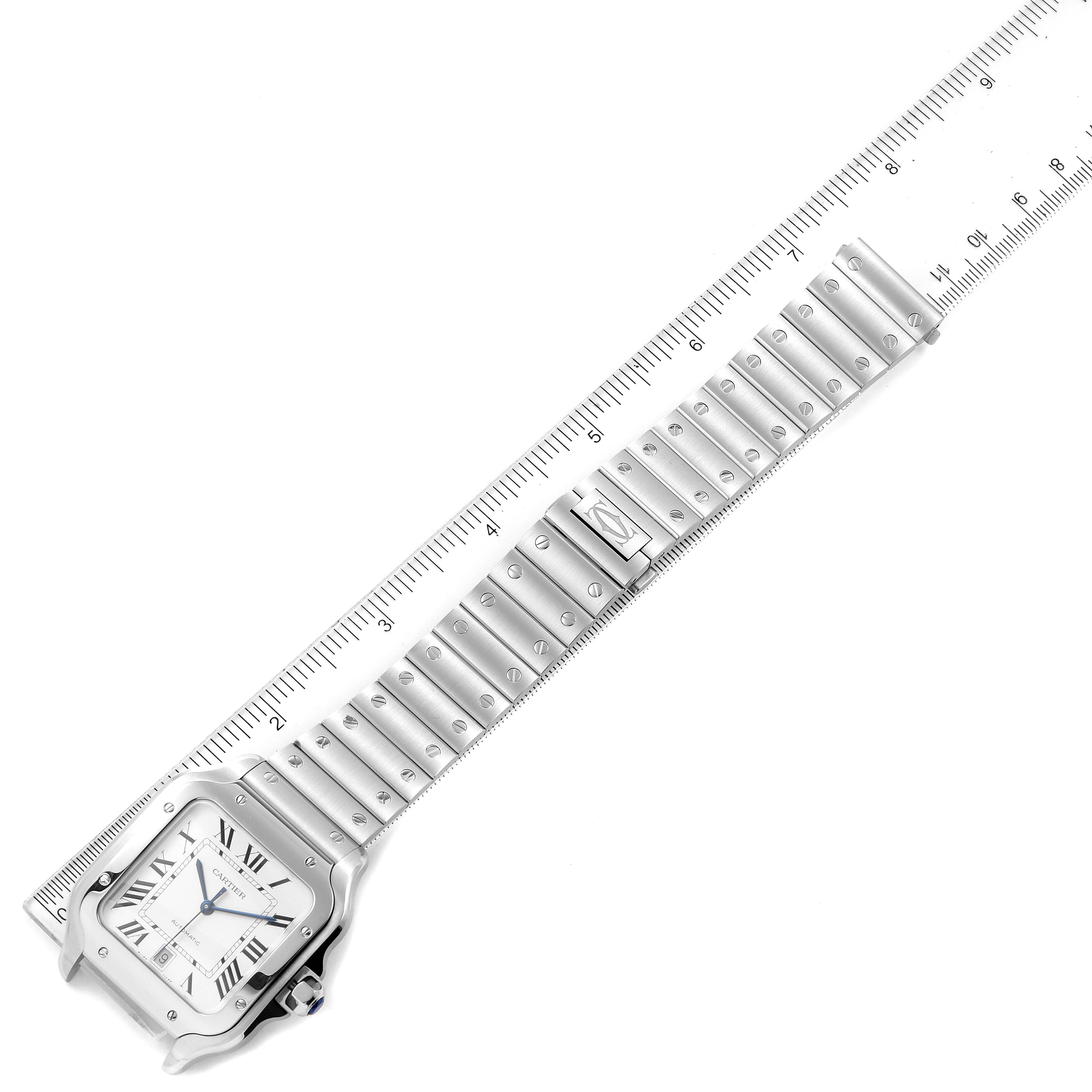 The image shows the Cartier Santos WSSA0018 Men's Stainless Steel Silver Dial WSSA0018 Men's Stainless Steel Silver Dial watch laid flat next to a ruler, highlighting the band and square face with Roman numerals.