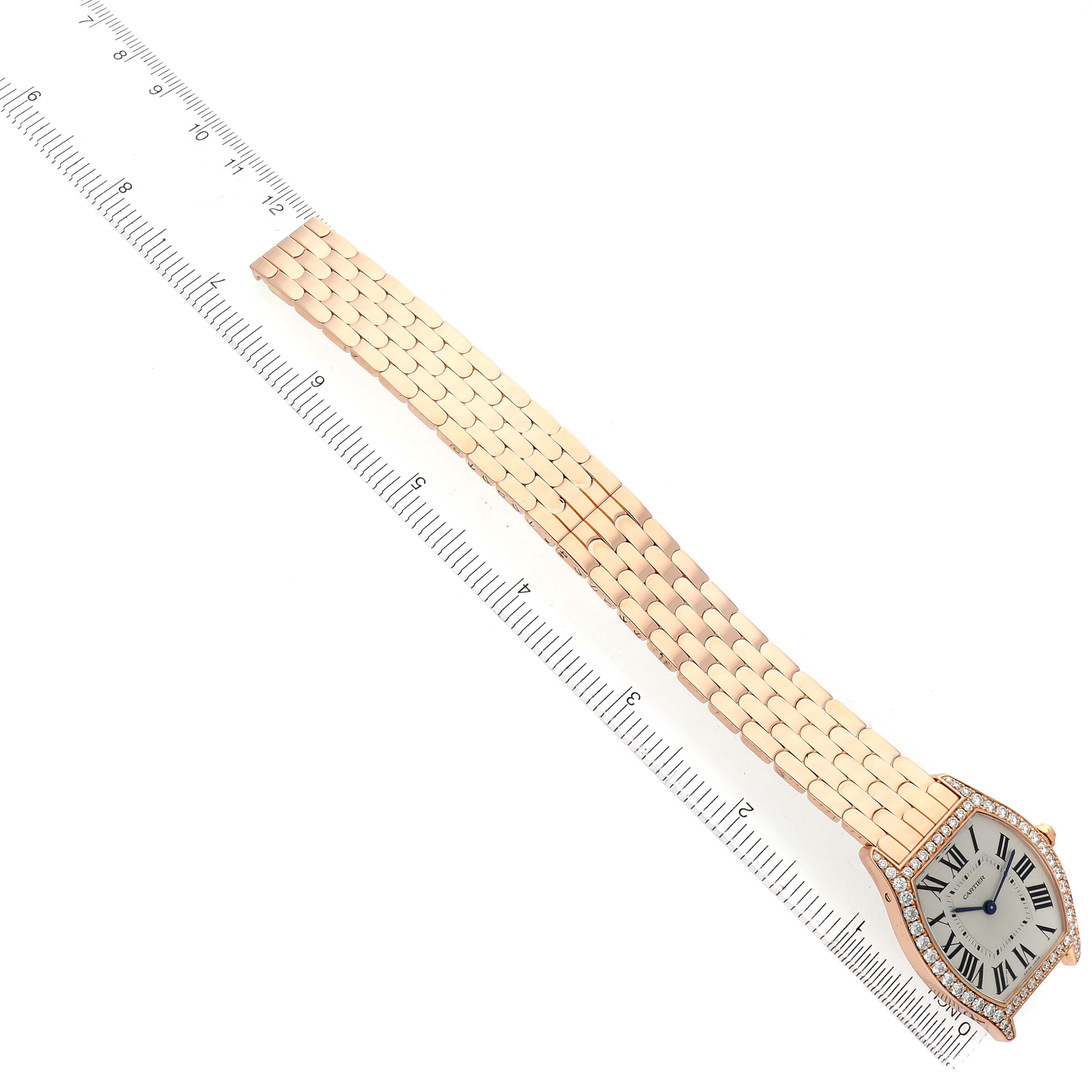 The Cartier Tortue WA501012 Women's Rose Gold Silver Dial watch is shown at an angle, highlighting its face and full bracelet alongside a ruler for scale.