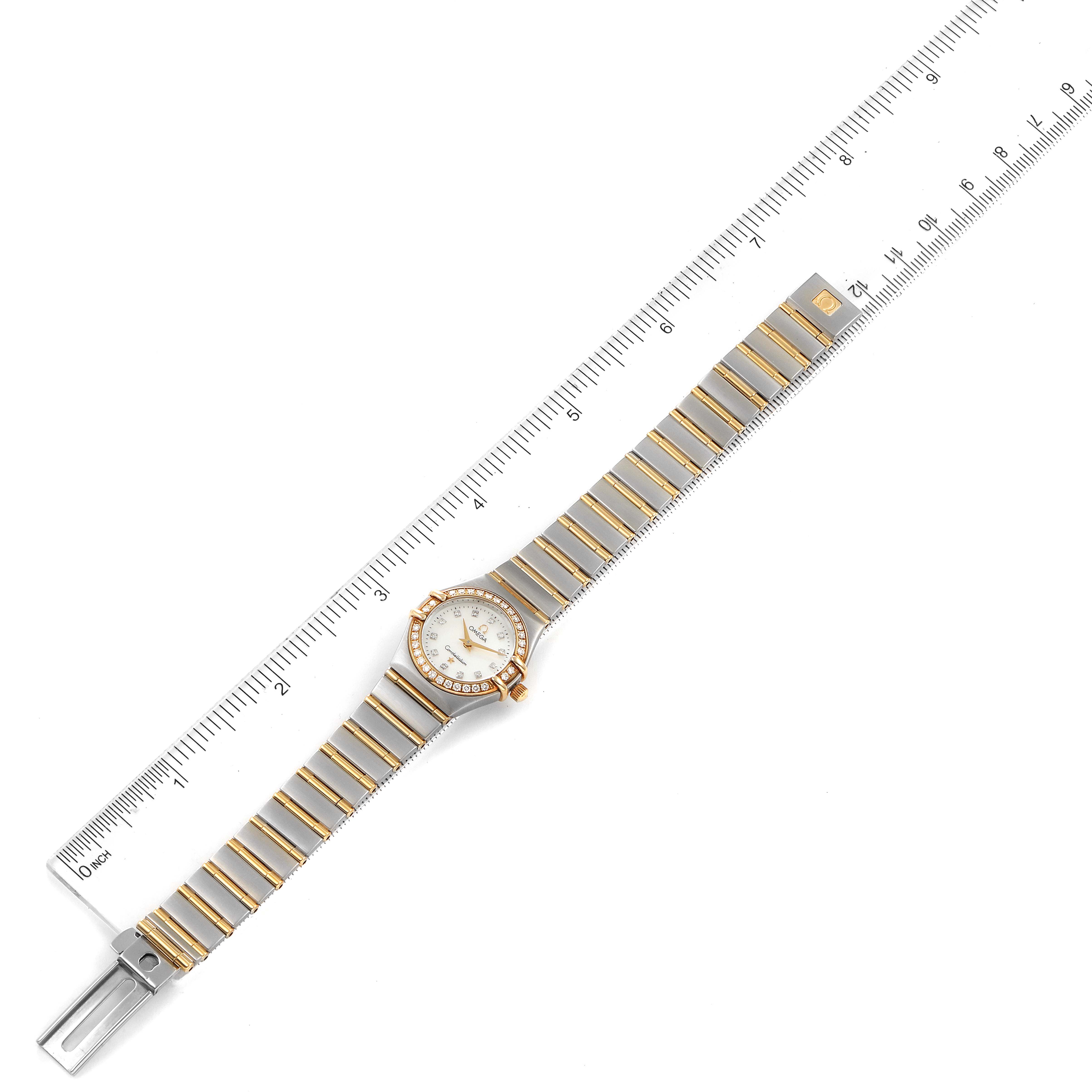 The Omega 1267.75.00 Women's Steel and Gold (two tone) Mother of Pearl Dial 1267.75.00 Women's Steel and Gold (two tone) Mother of Pearl Dial Constellation 95 Mother of Pearl Diamond Watch 1267.75.00 is shown flat, with the full length of the band and face visible alongside a ruler.