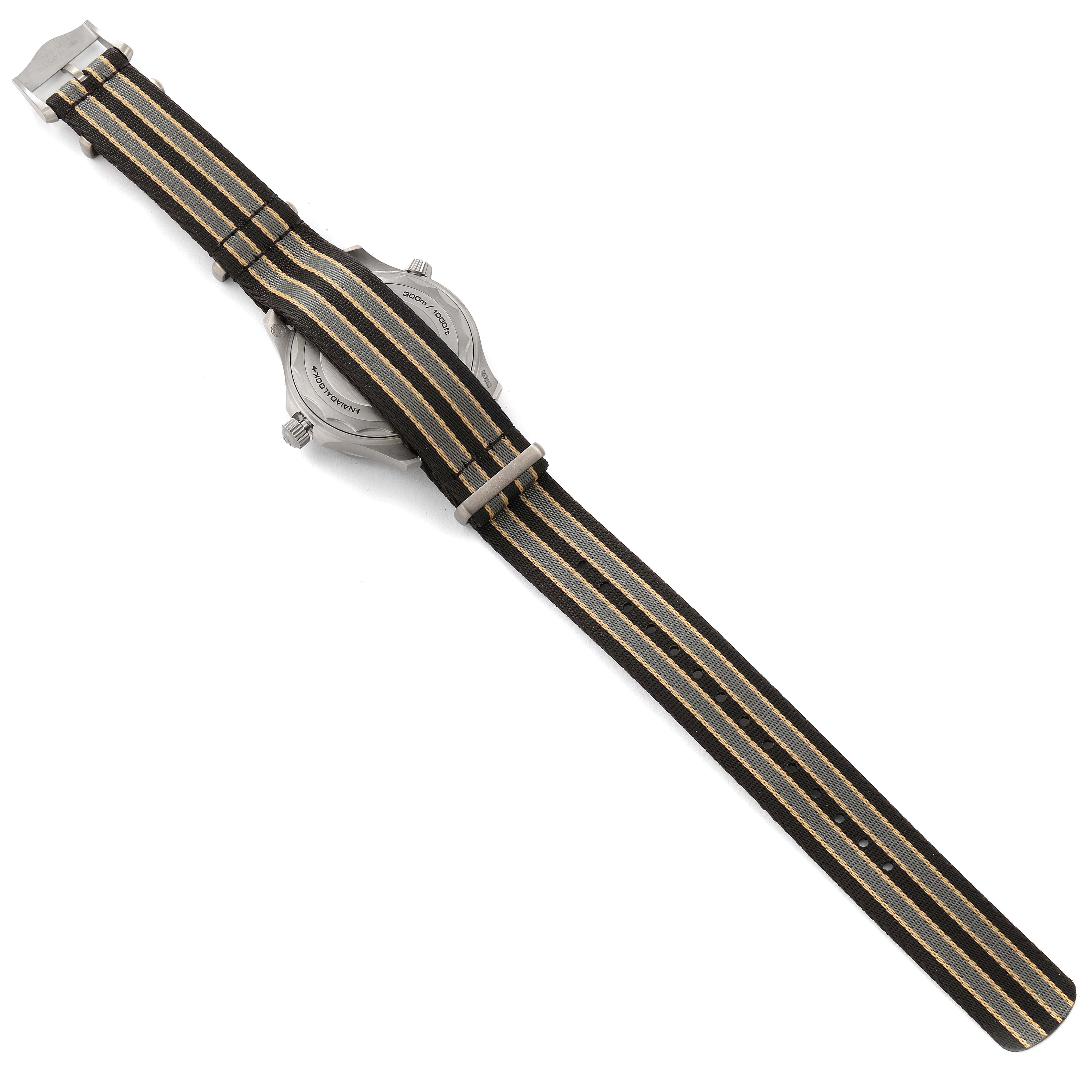 The image shows the backside of an Omega Seamaster 210.92.42.20.01.001 Men's Titanium Brown Dial 210.92.42.20.01.001 Men's Titanium Brown Dial watch with a striped fabric strap.