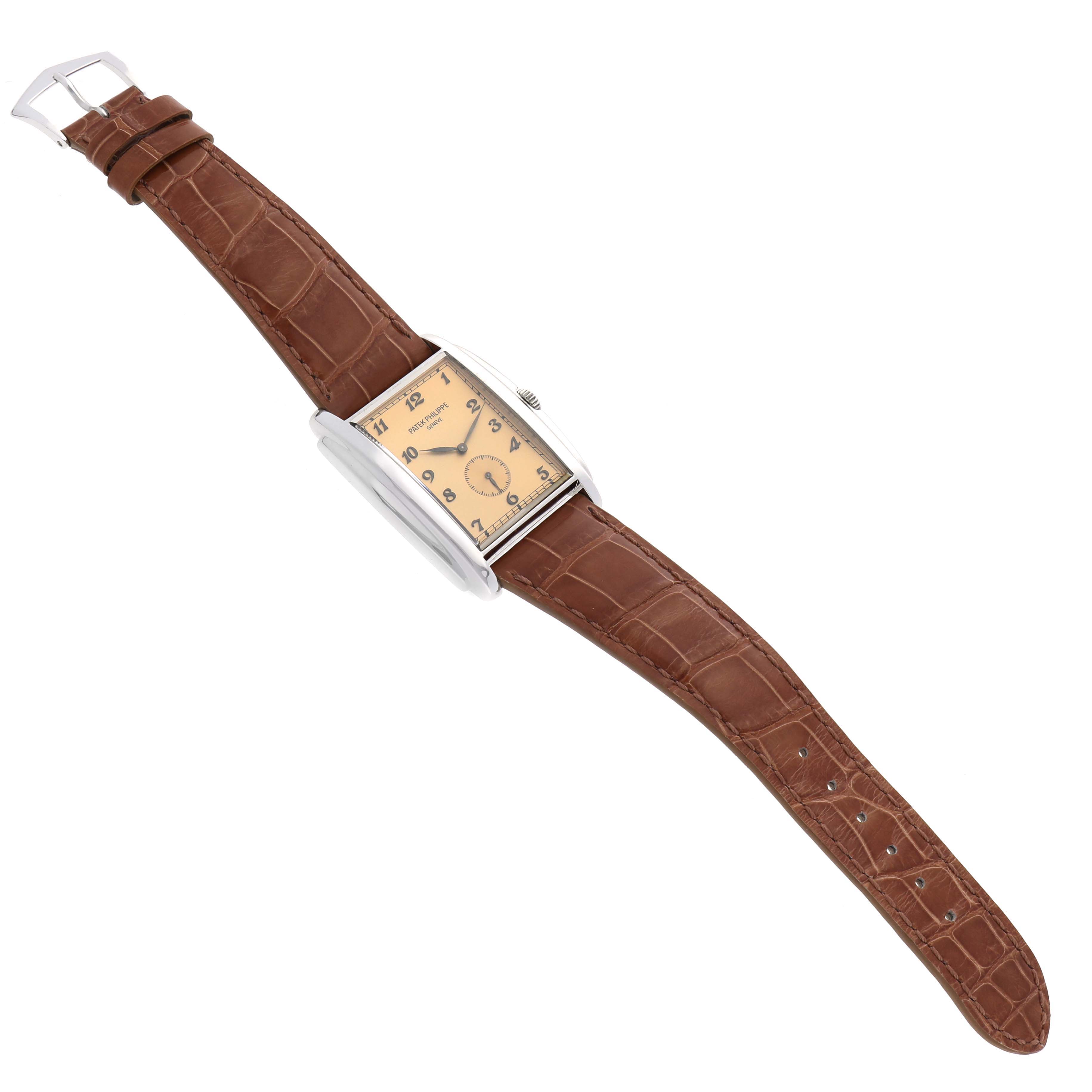 The Patek Philippe Gondolo 5124G Men's White Gold Brown Dial watch is shown from an overhead angle, displaying the rectangular dial, elegant hands, and brown leather strap.
