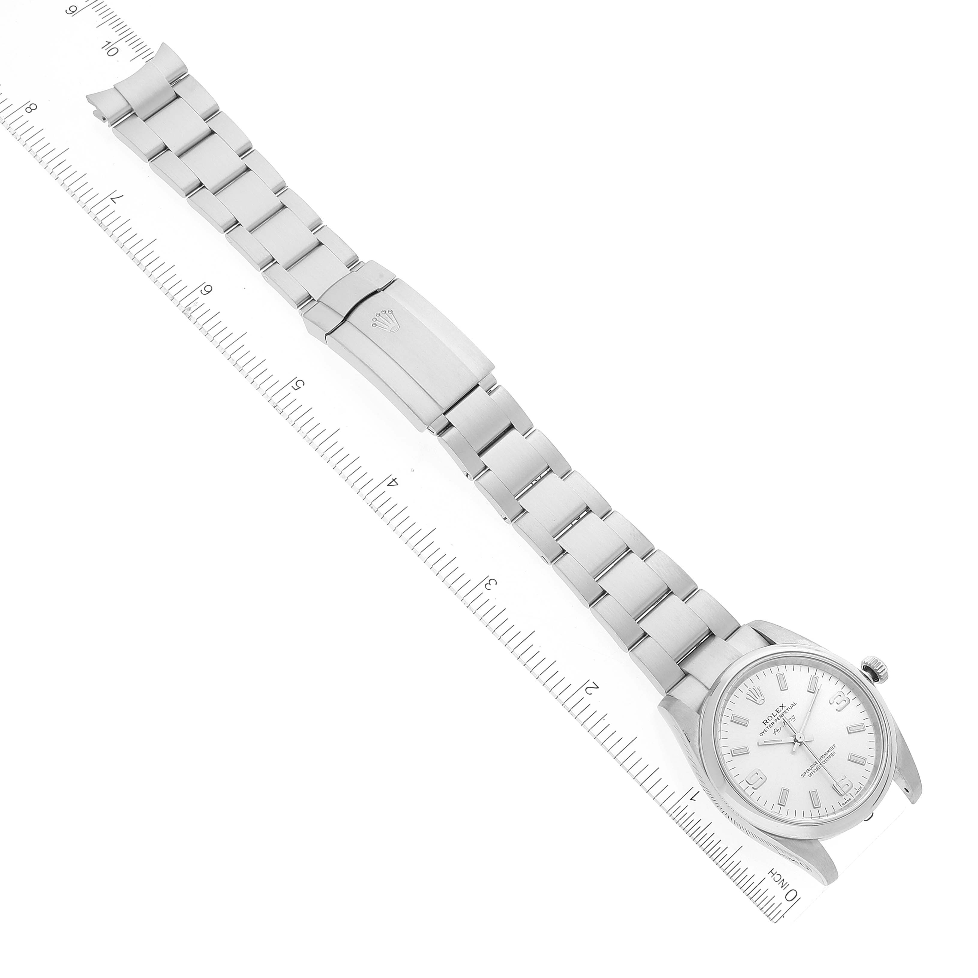 The image shows a top-down view of a Rolex Air-King 114200 Men's Stainless Steel Silver Dial 114200 Men's Stainless Steel Silver Dial watch with its full metal bracelet and clasp extended, along with a measuring scale.