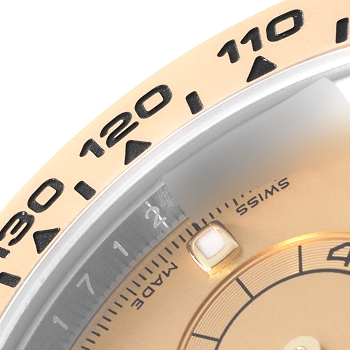 This close-up image of a Rolex Daytona 116503 Men's Steel and Gold (two tone) Champagne Dial 116503 Men's Steel and Gold (two tone) Champagne Dial watch shows part of the bezel with speed markers and a section of the dial.