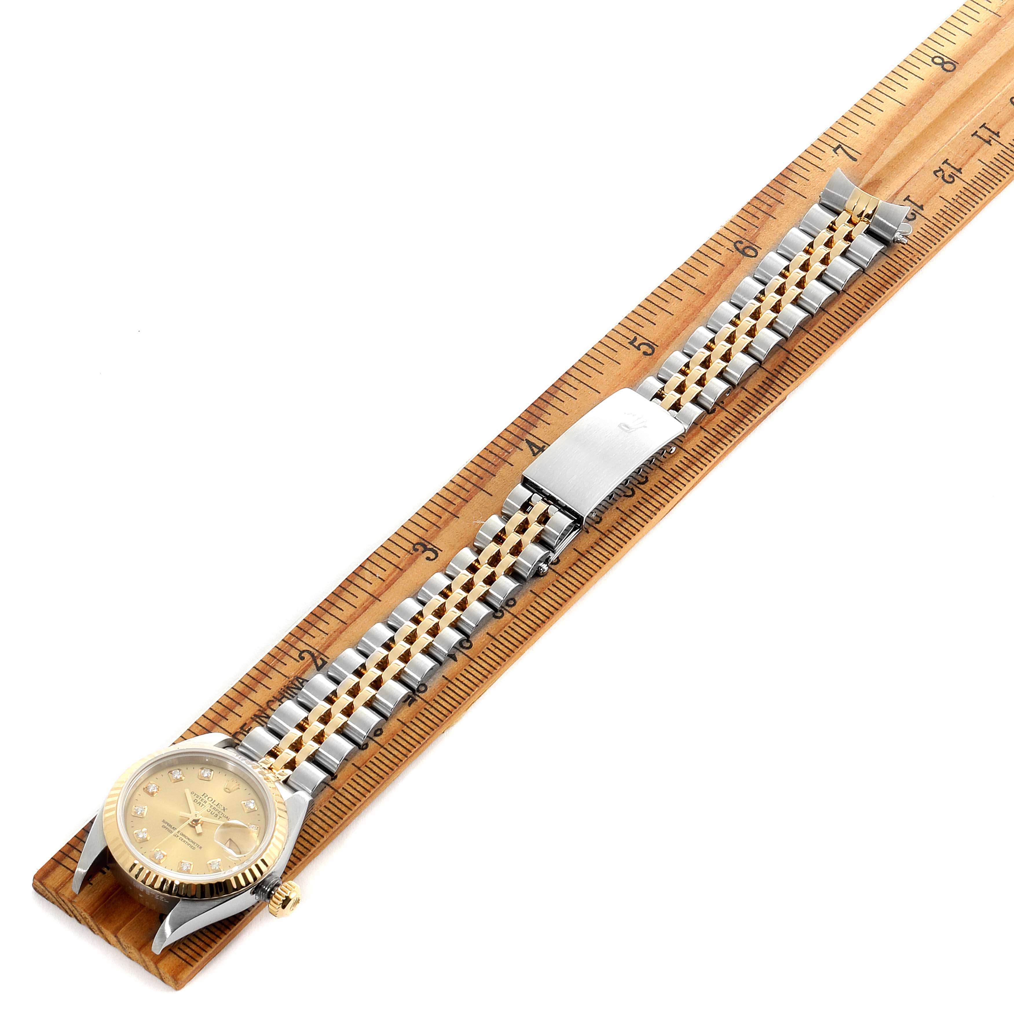 A Rolex Datejust 69173 Women's Steel and Gold (two tone) Champagne Dial 69173 Women's Steel and Gold (two tone) Champagne Dial watch is placed flat against a ruler, displaying its gold and silver jubilee bracelet and face.