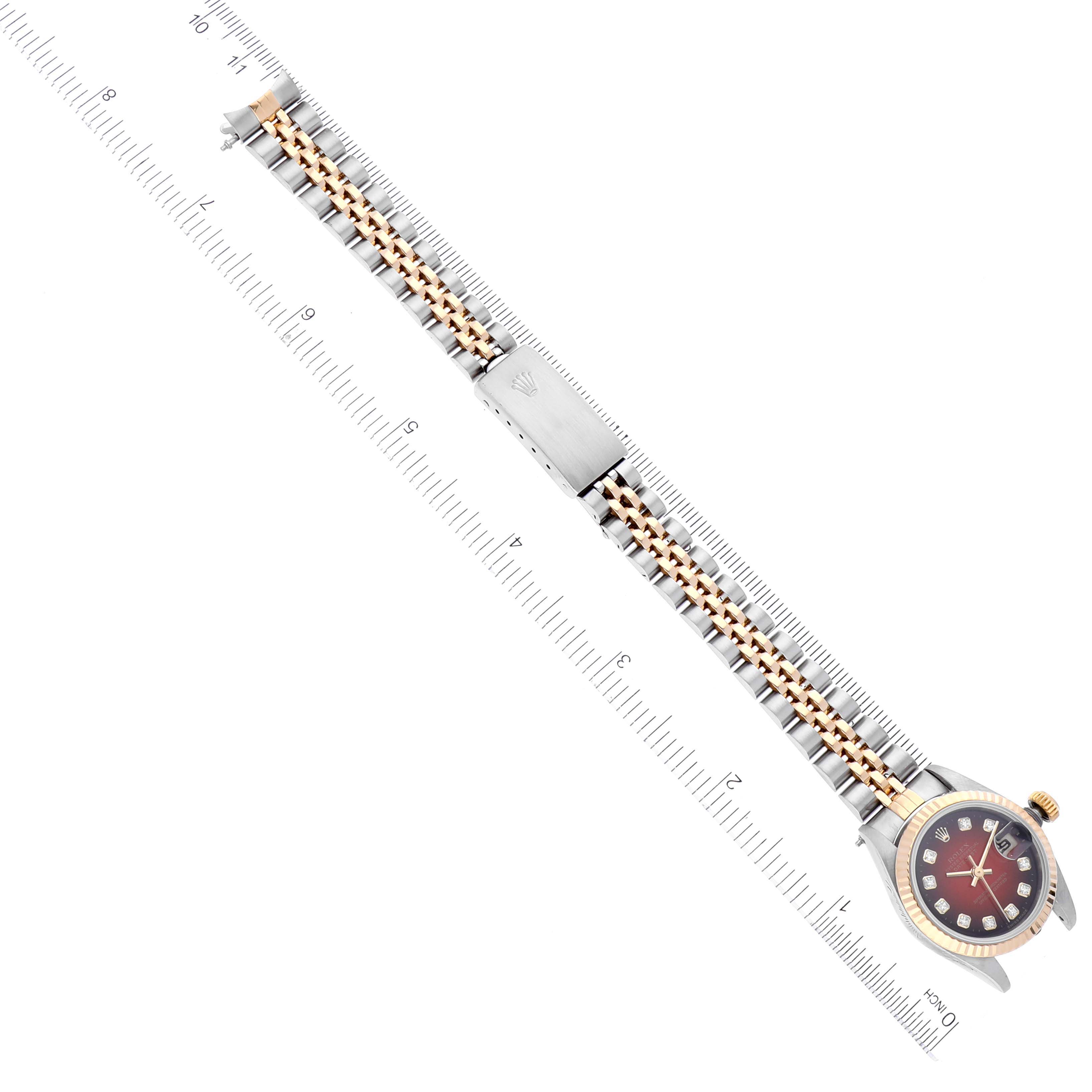The Rolex Datejust 69173 Women's Steel and Gold (two tone) Red Dial 69173 Women's Steel and Gold (two tone) Red Dial watch is shown from a top-angle view, displaying the face, bezel, and entire bracelet against a ruler for size reference.