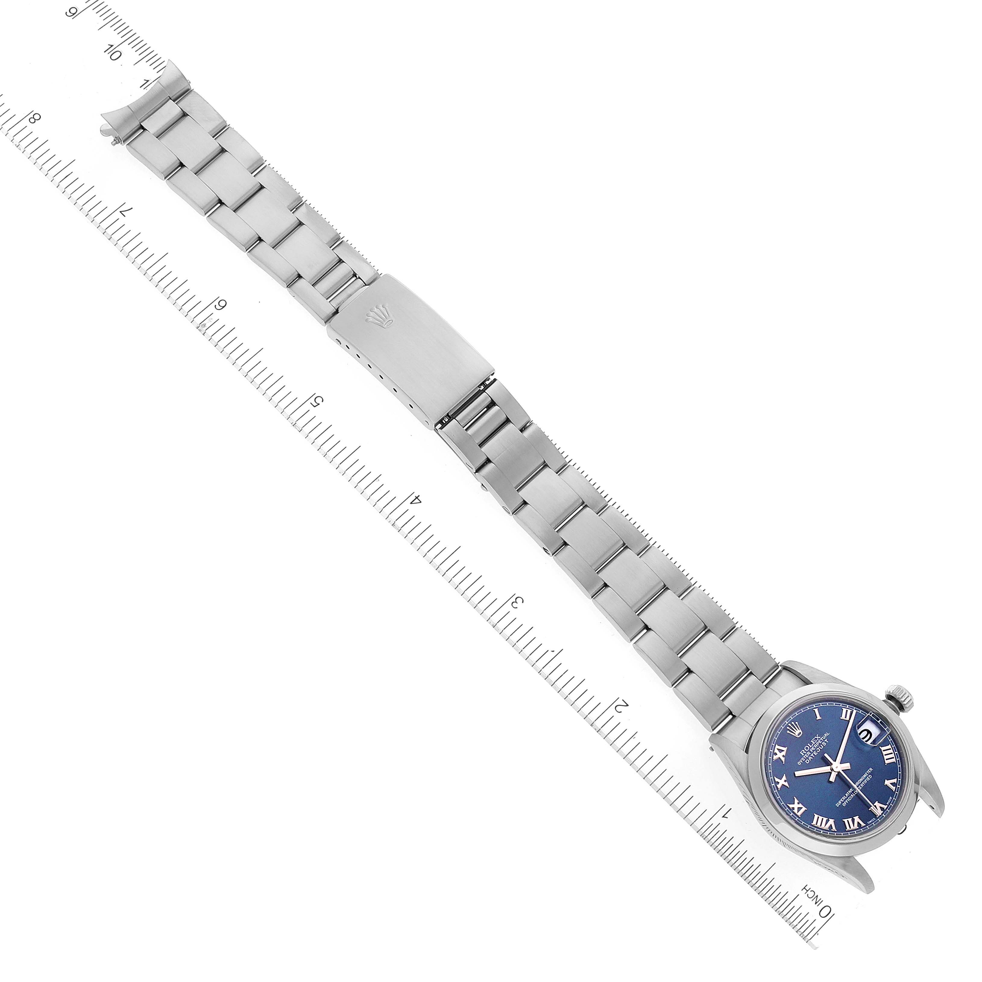 This image shows a top-down view of a Rolex Mid-Size 78240 Women
s Stainless Steel Blue Dial 78240 Women
s Stainless Steel Blue Dial watch with a blue dial, stainless steel case, and bracelet, alongside a ruler.