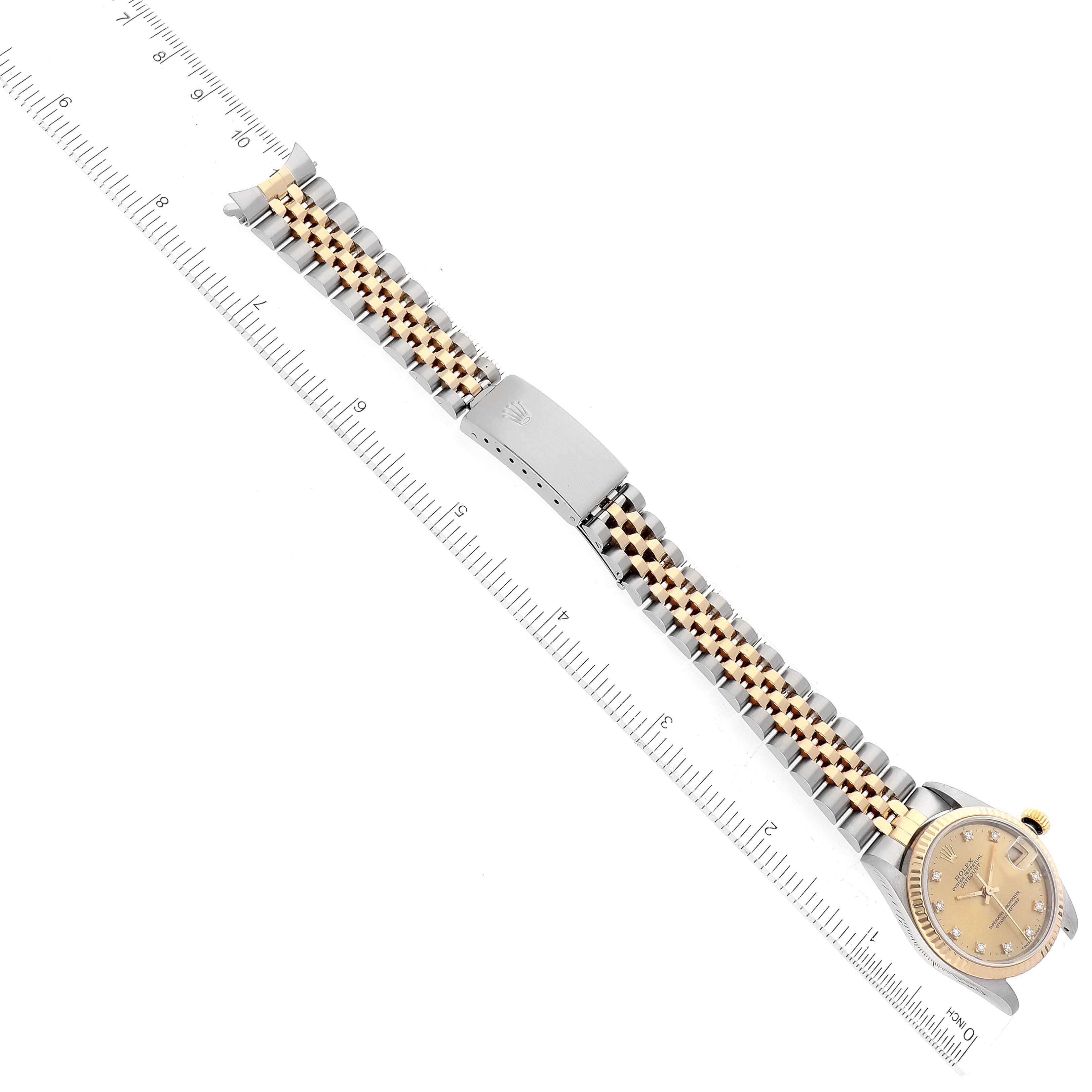 The image shows a Rolex Mid-Size 68273 Women's Steel and Gold (two tone) Champagne Dial 68273 Women's Steel and Gold (two tone) Champagne Dial watch laid flat, viewed from above, with a focus on its band and clasp against a measuring ruler.