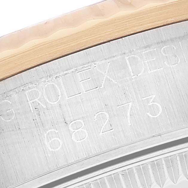 This image shows the side angle of a Mid-Size Rolex model, specifically the engraved serial number and part of the bezel.