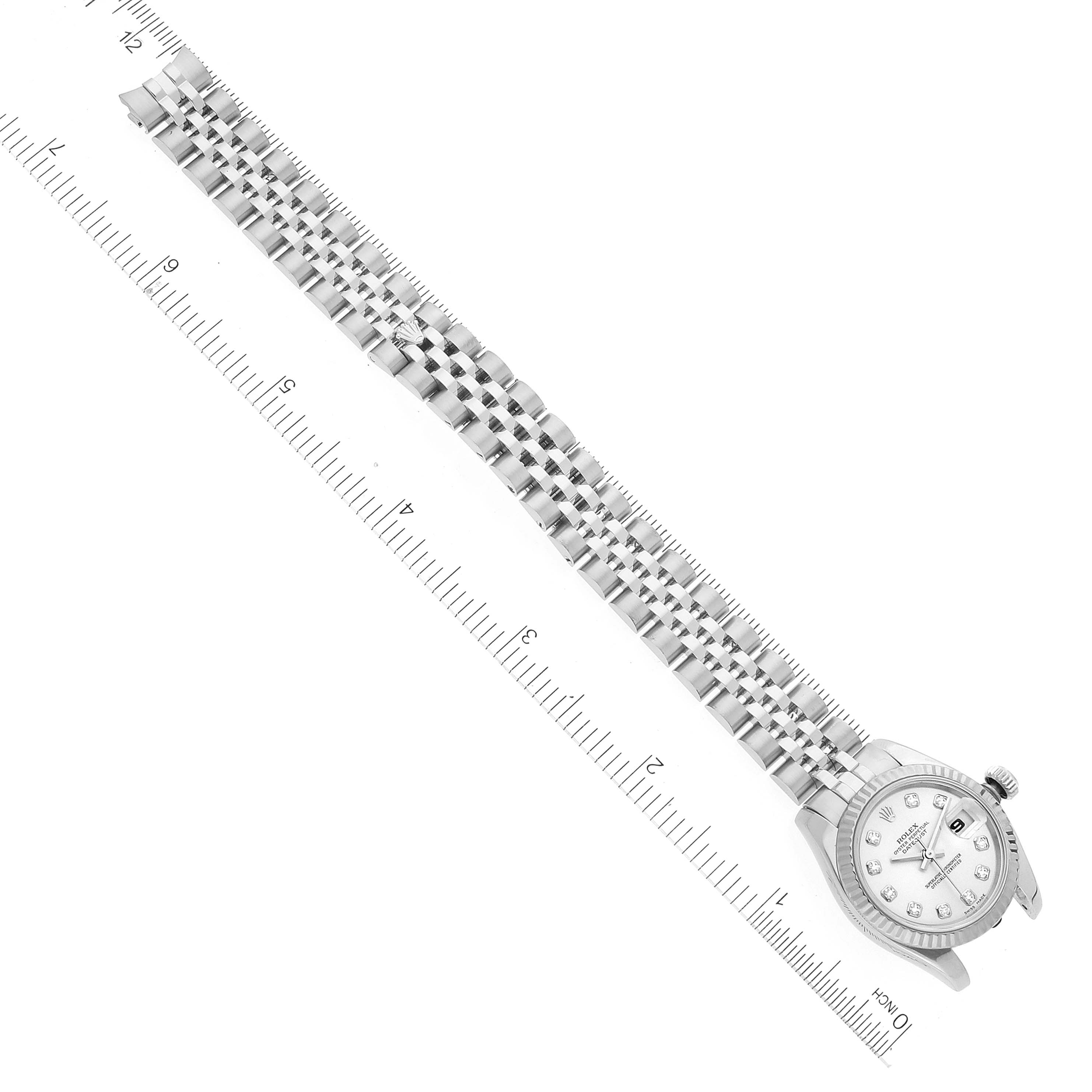 The image shows a top-down view of a Rolex Datejust 179174 Women's Stainless Steel Silver Dial 179174 Women's Stainless Steel Silver Dial watch with its bracelet extended next to a ruler for scale.
