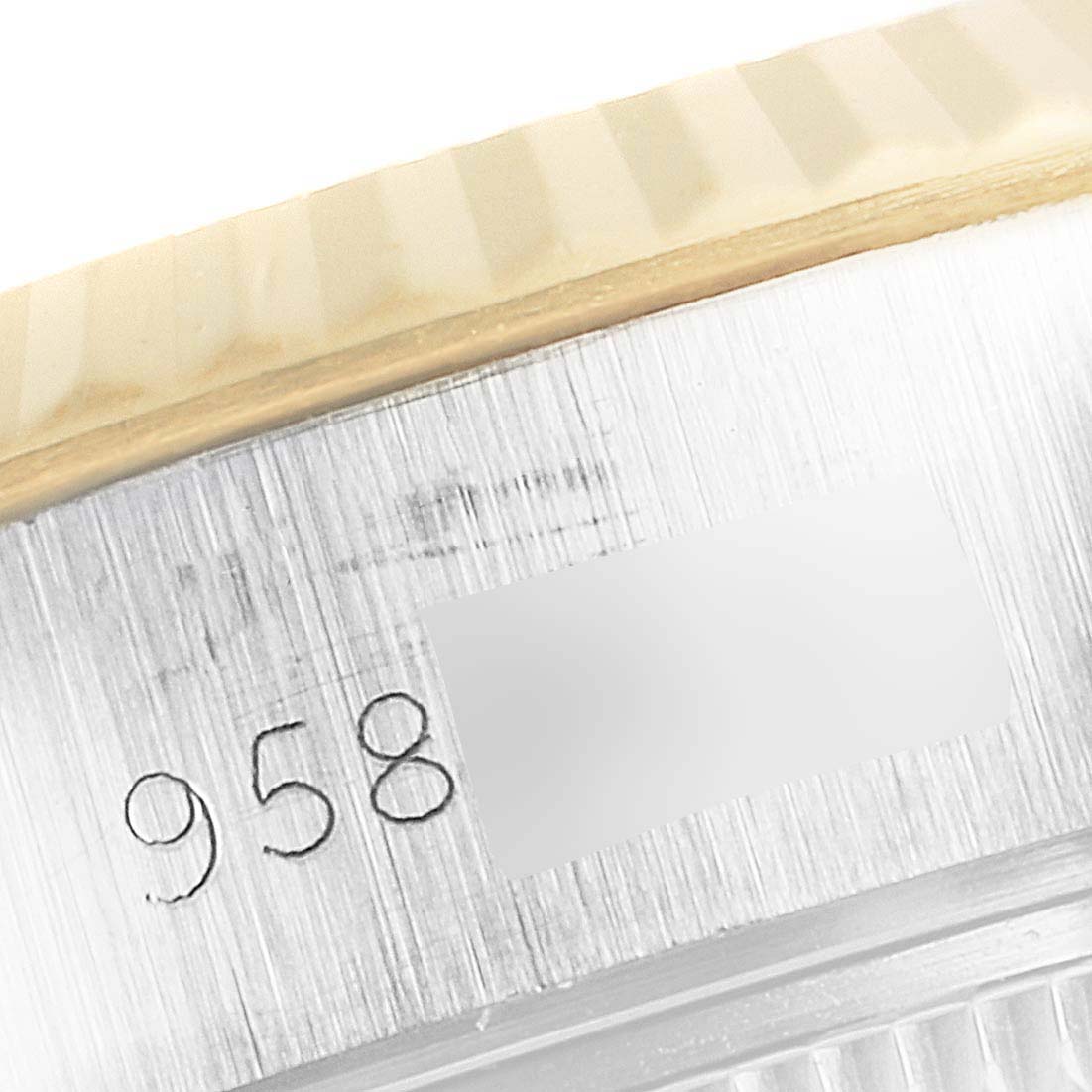 The image shows a close-up angle of the side of a Rolex Datejust 69173 Women
s Steel and Gold (two tone) Champagne Dial 69173 Women
s Steel and Gold (two tone) Champagne Dial watch, focusing on part of the fluted bezel and serial number engraving.