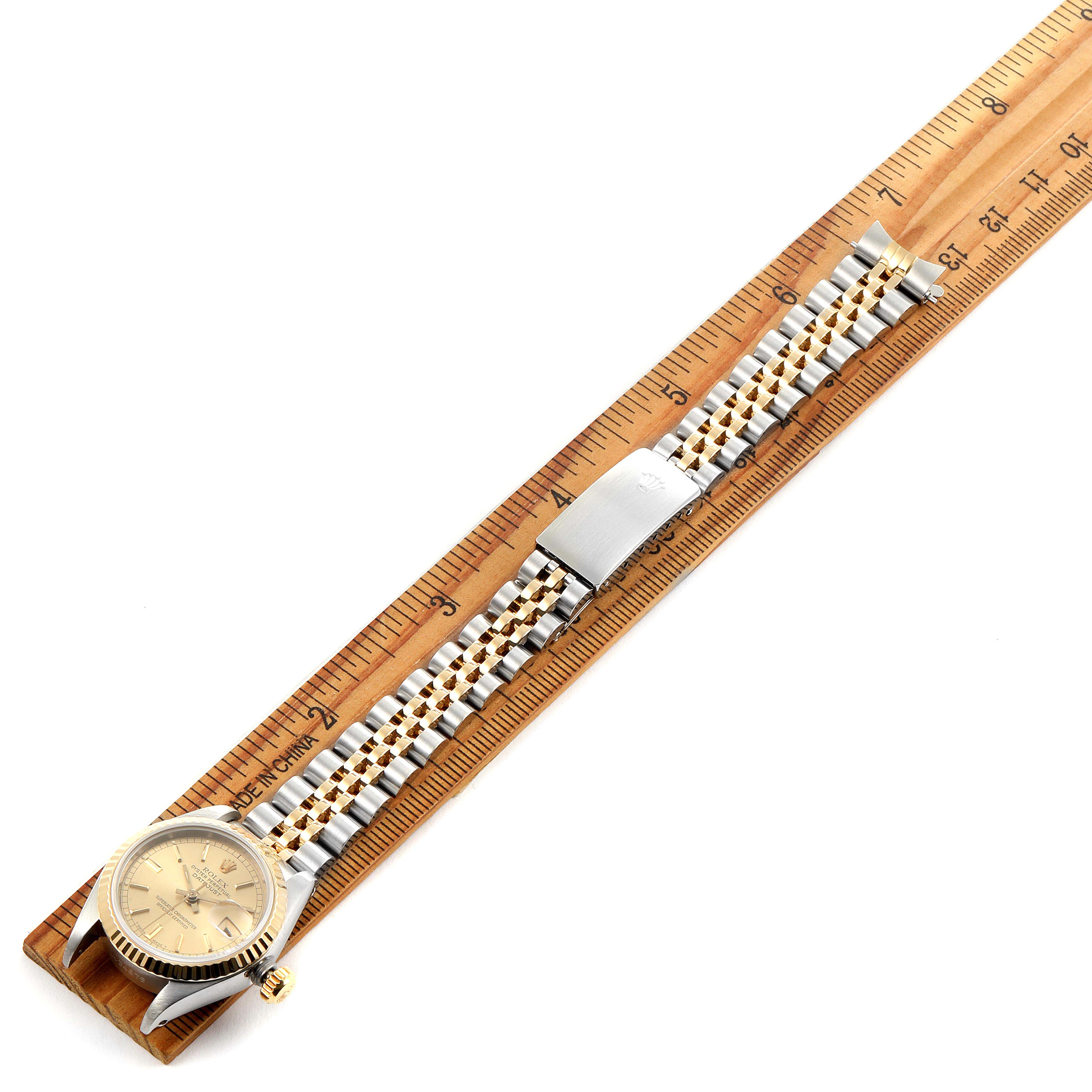 The image shows a Rolex Datejust 69173 Women's Steel and Gold (two tone) Champagne Dial 69173 Women's Steel and Gold (two tone) Champagne Dial watch laid flat on a ruler, showcasing its face, case, and two-tone bracelet.