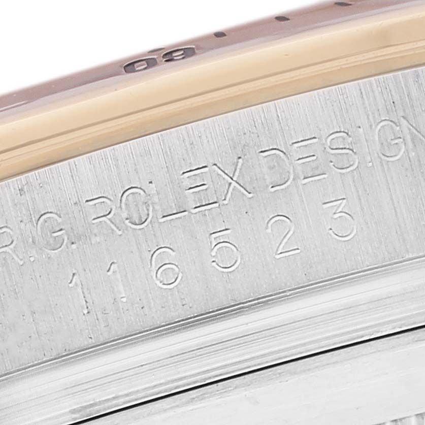 This image shows a close-up of the engraved serial number and design text on the casing of a Rolex Daytona 116523 Men's Steel and Gold (two tone) Mother of Pearl Dial 116523 Men's Steel and Gold (two tone) Mother of Pearl Dial watch.