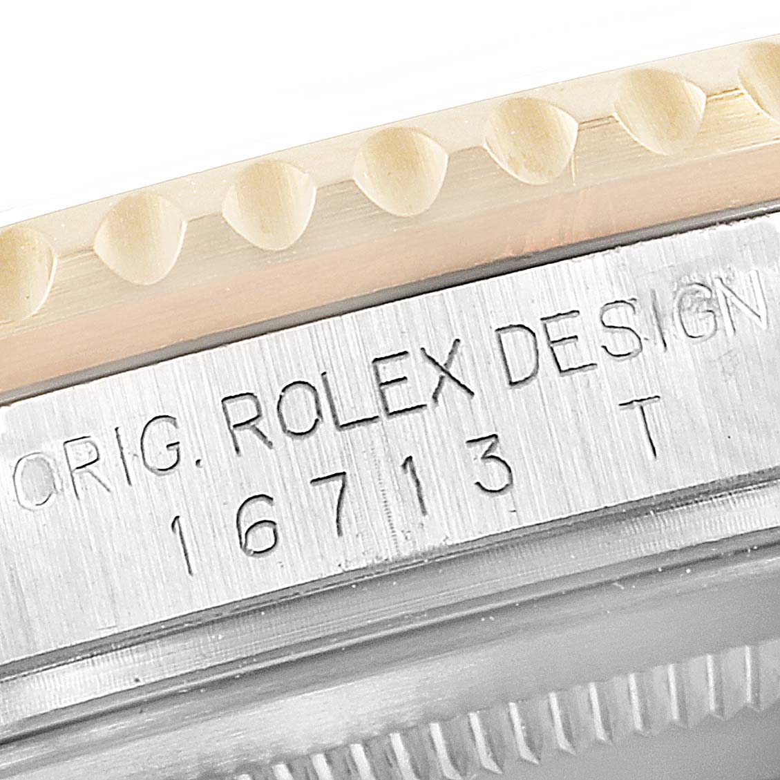 The image shows a close-up of the bezel and engraved case serial number of a Rolex GMT-Master 16713 Men's Steel and Gold (two tone) Black Dial 16713 Men's Steel and Gold (two tone) Black Dial model.