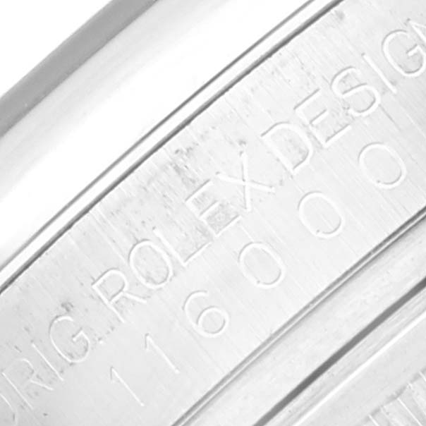 The image shows a close-up of the engraved side of the bezel of a Rolex Oyster Perpetual 116000 Men's Stainless Steel Purple Dial 116000 Men's Stainless Steel Purple Dial watch.