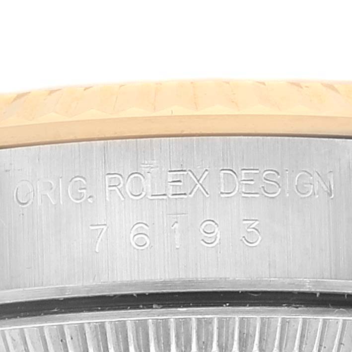 This image shows a close-up of the side of a Rolex Oyster Perpetual 76193 Women's Steel and Gold (two tone) Champagne Dial 76193 Women's Steel and Gold (two tone) Champagne Dial watch, displaying the model number 76193 and the engraving "Orig. Rolex Design."