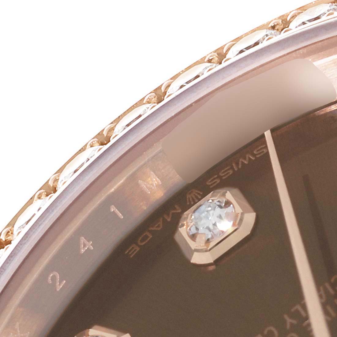 This close-up of the Rolex President 278285 Women's Rose Gold Brown Dial 278285 Women's Rose Gold Brown Dial watch shows part of the bezel, dial, and a diamond hour marker.