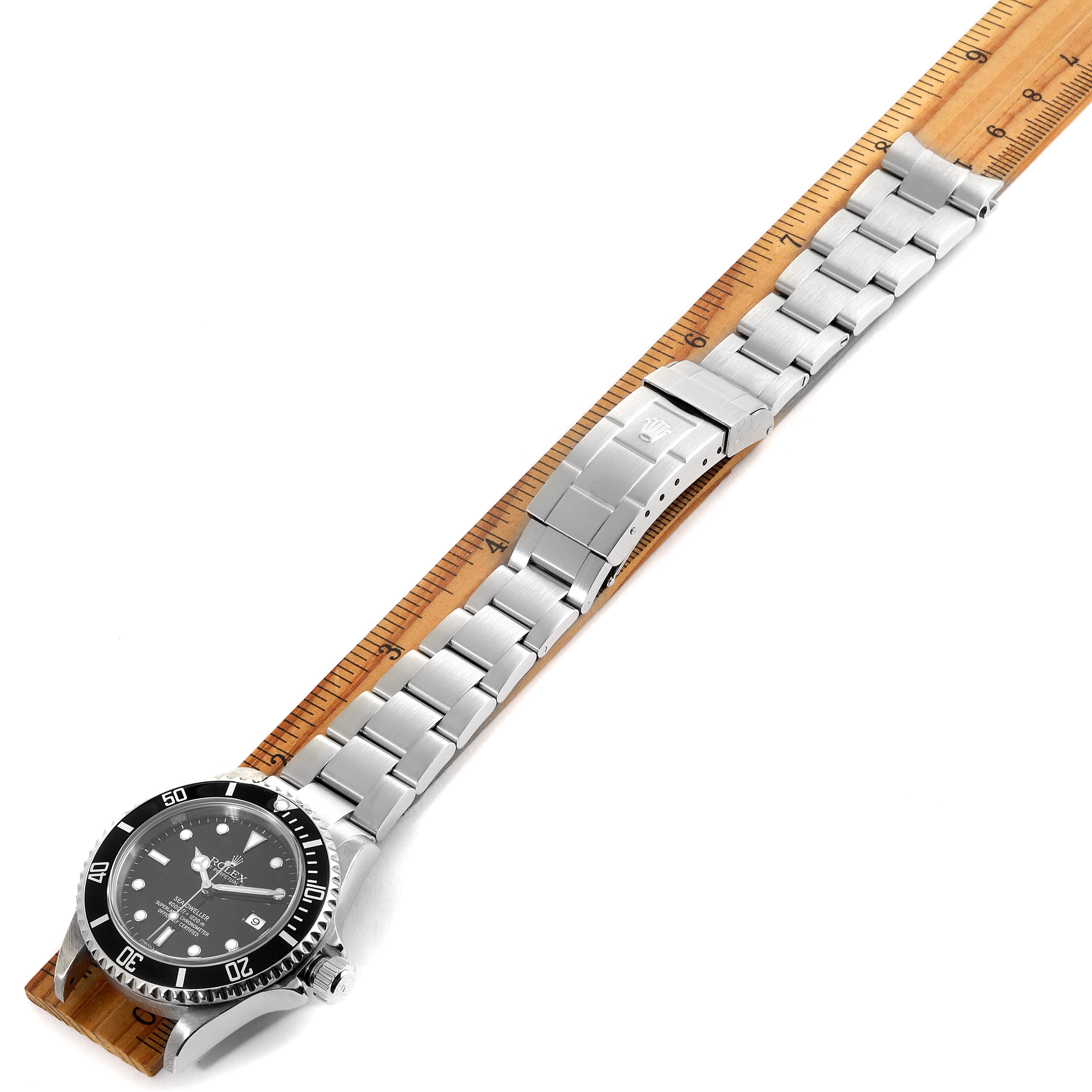 This is an overhead view of the Rolex Sea-Dweller 16600 Men
s Stainless Steel Black Dial 16600 Men
s Stainless Steel Black Dial watch, showing the face, bezel, and entire metal bracelet laid next to a ruler.