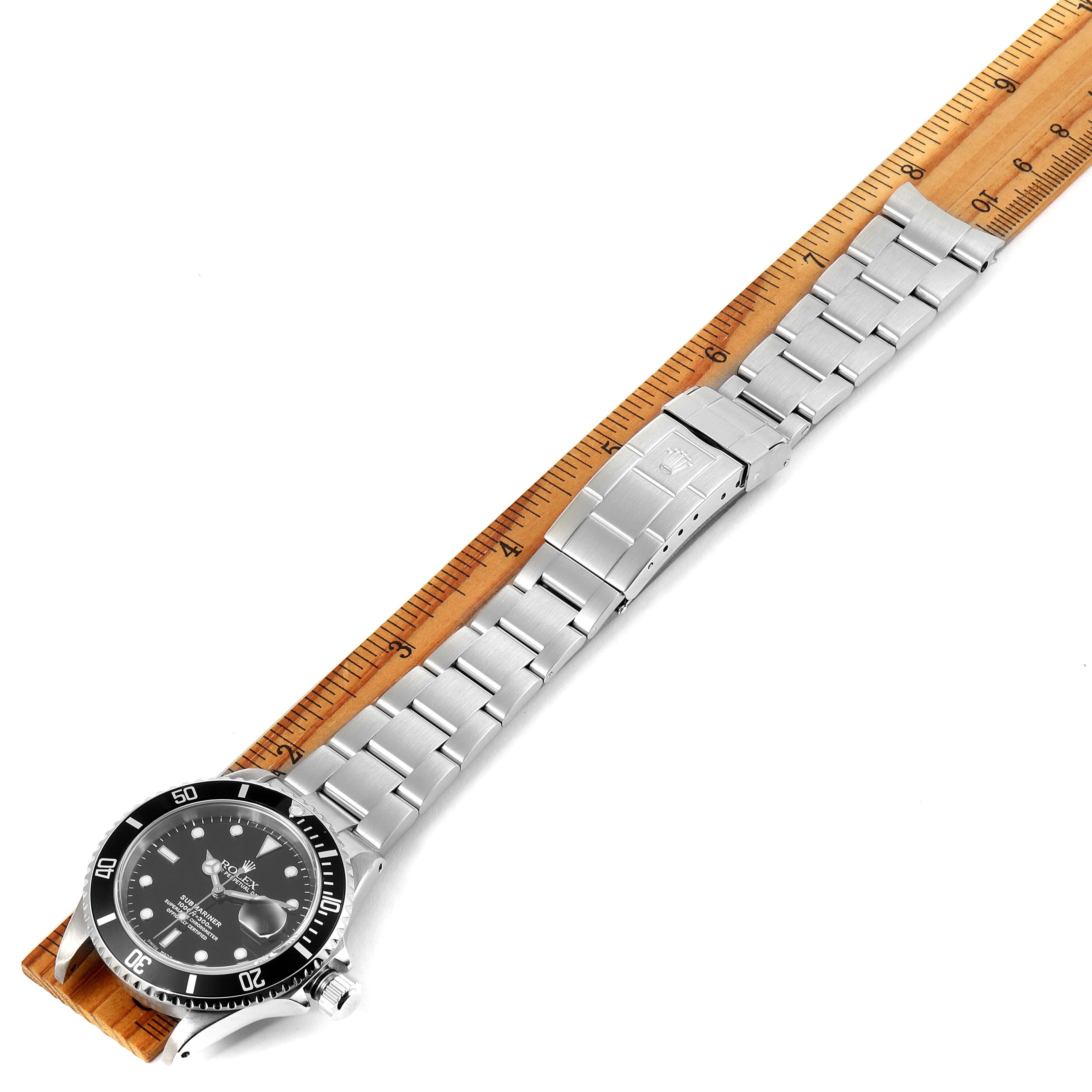 The image shows a Rolex Submariner 16610 Men
s Stainless Steel Black Dial 16610 Men
s Stainless Steel Black Dial watch laid flat, displaying the full length of the band alongside a ruler.