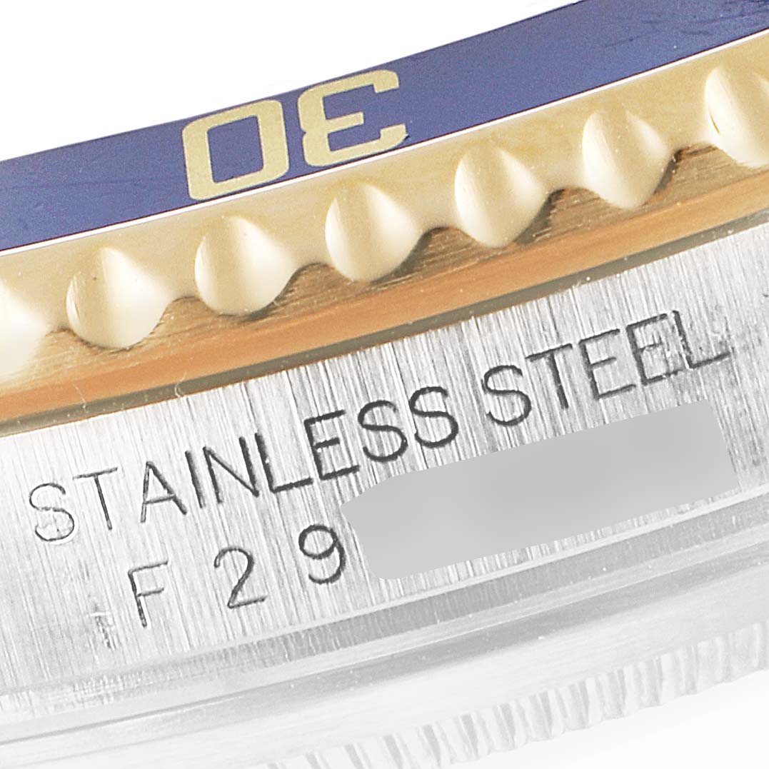 This close-up image shows the bezel and stainless steel case side of a Rolex Submariner 16613 Men's Steel and Gold (two tone) Champagne Dial 16613 Men's Steel and Gold (two tone) Champagne Dial watch, including part of its engraved text.