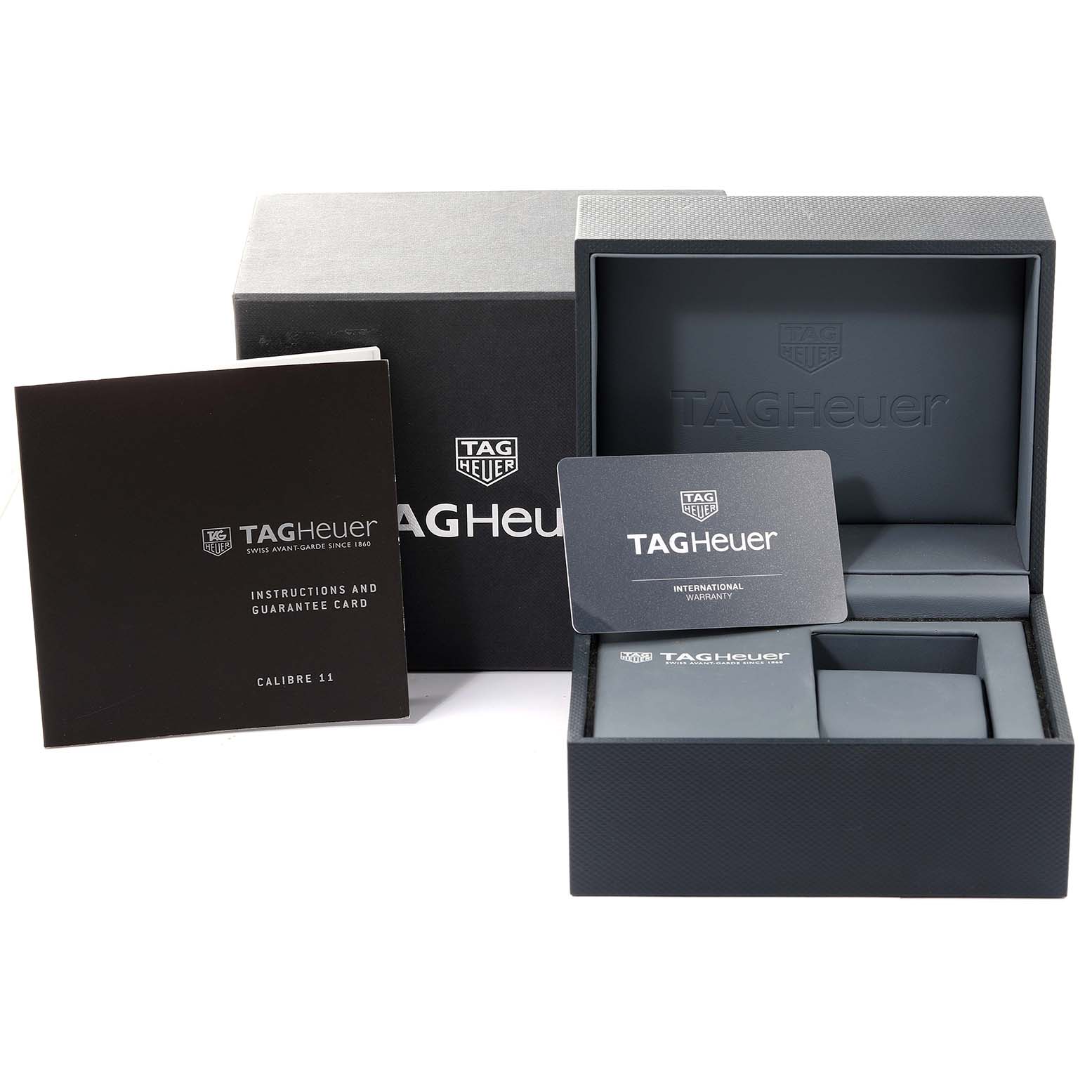 The image shows the packaging, instruction booklet, guarantee card, and storage box for the Tag Heuer Monaco watch.