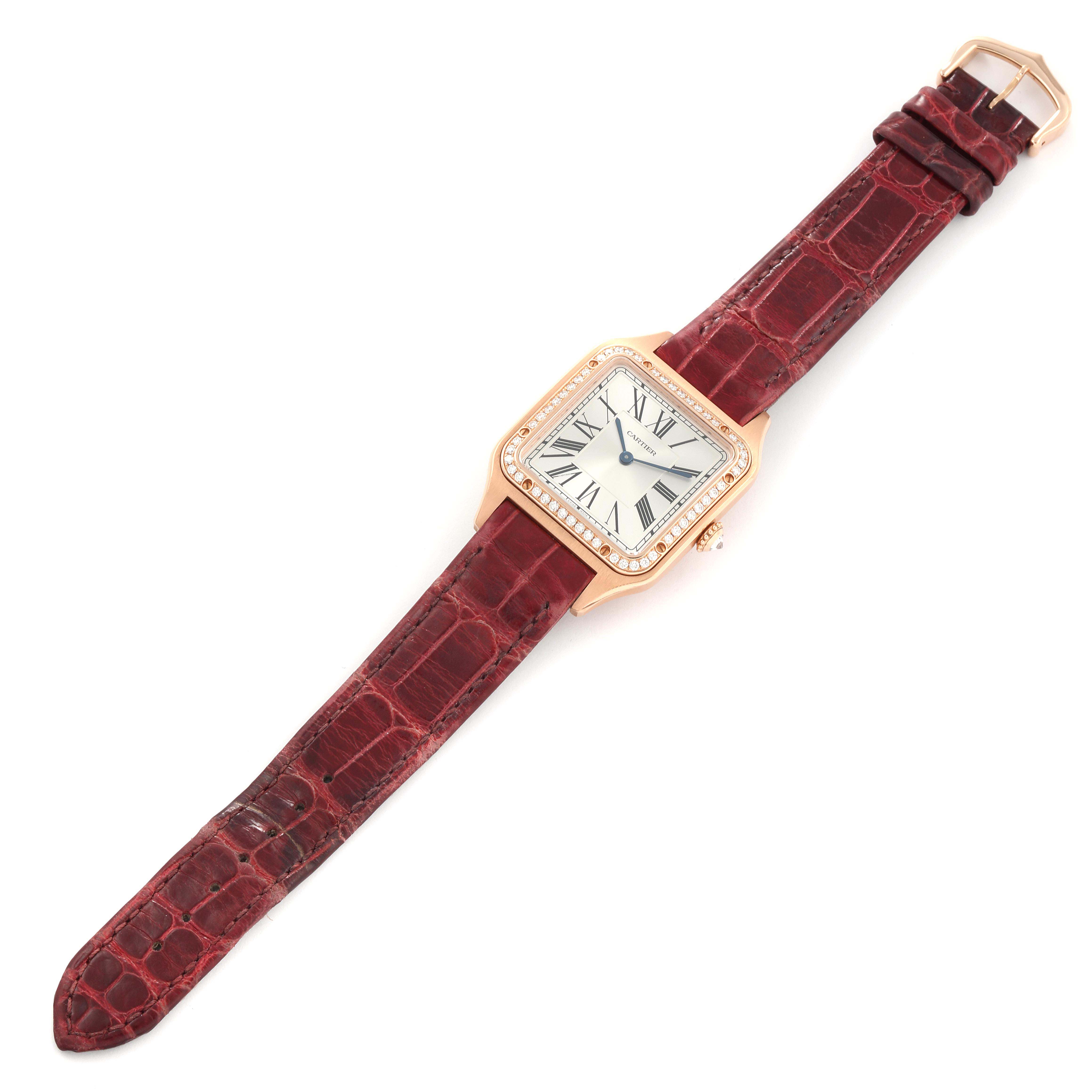 The Cartier Santos WJSA0016 Women's Rose Gold Silver Dial WJSA0016 Women's Rose Gold Silver Dial watch is shown from a top-down angle, displaying its square face, Roman numerals, and red leather strap.