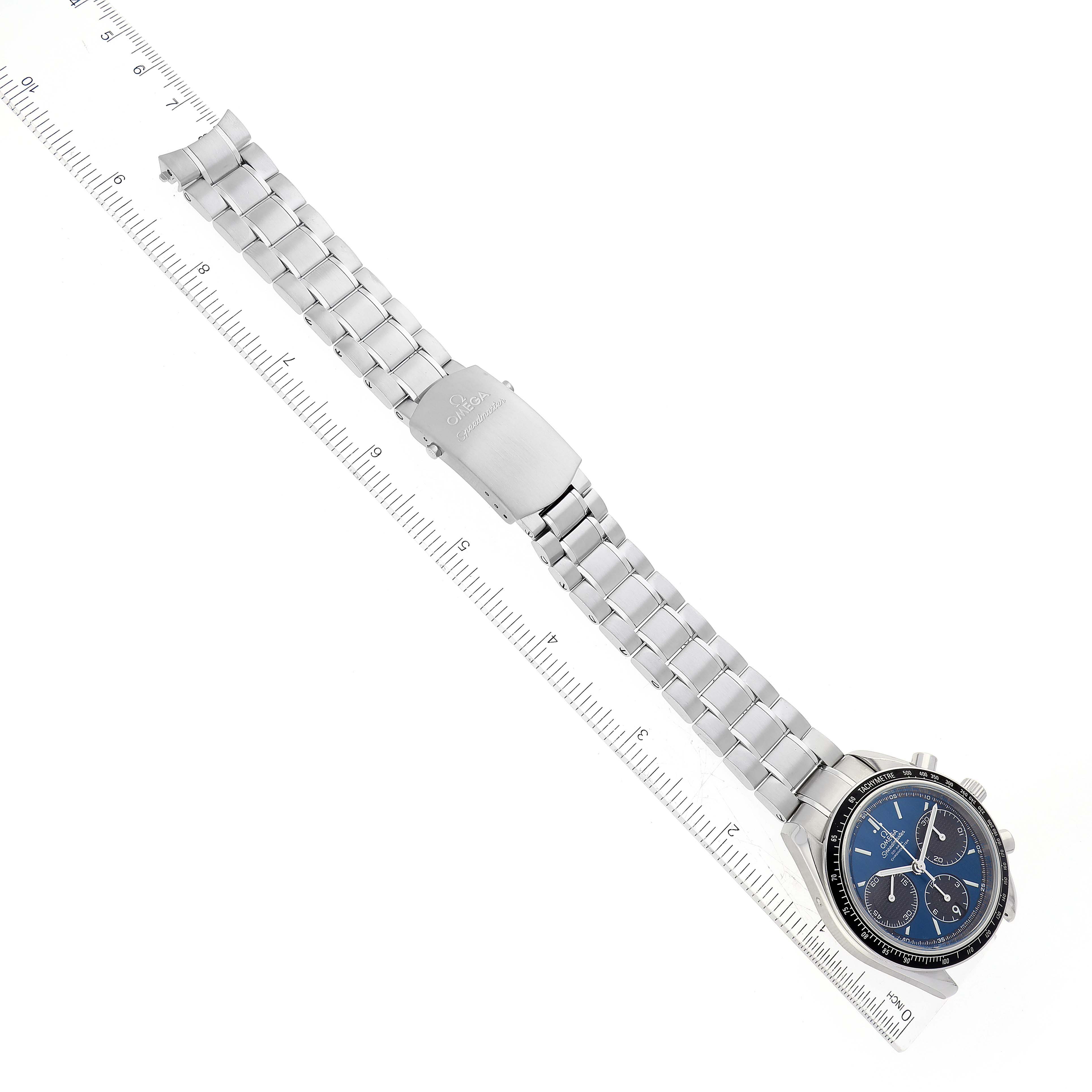 The Omega Speedmaster 326.30.40.50.03.001 Men
s Stainless Steel Blue Dial 326.30.40.50.03.001 Men
s Stainless Steel Blue Dial watch is shown from a top-down angle, with its face, bracelet, and clasp visible, alongside a ruler.